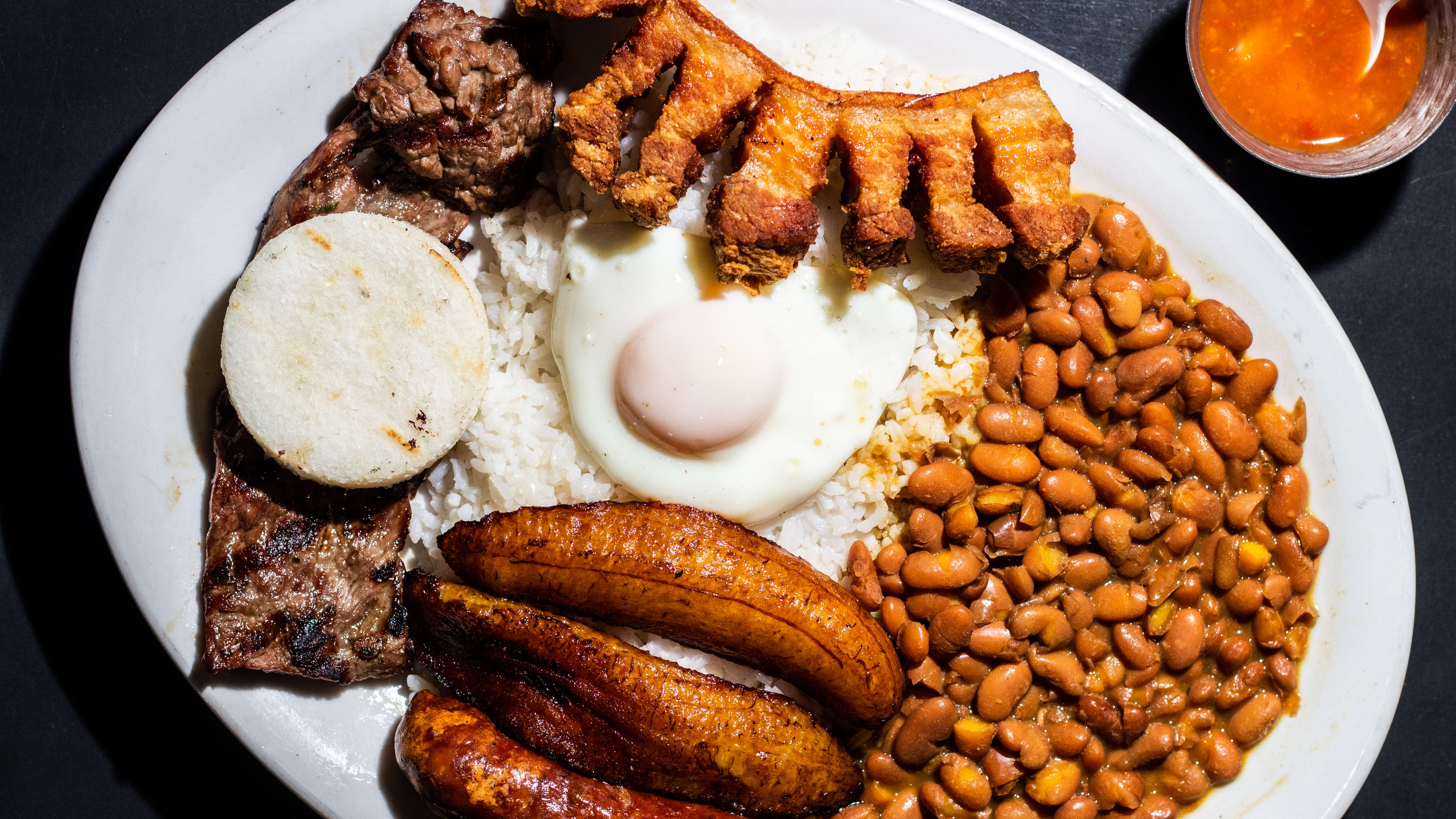 A bandeja paisa with egg, beans, chicharron, plantains and steak.