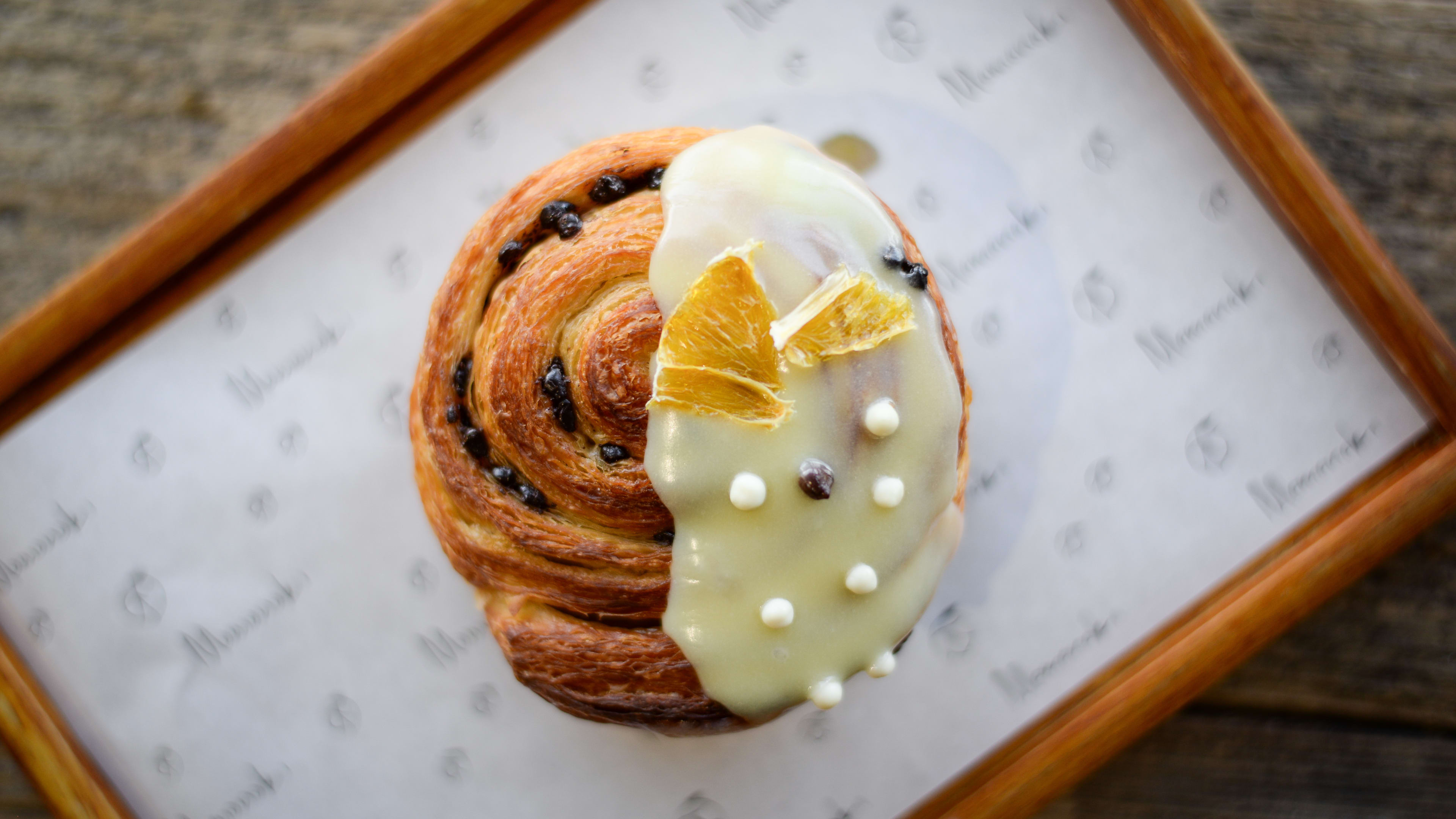 Pastry bun half dipped with white chocolate and dried oranges.