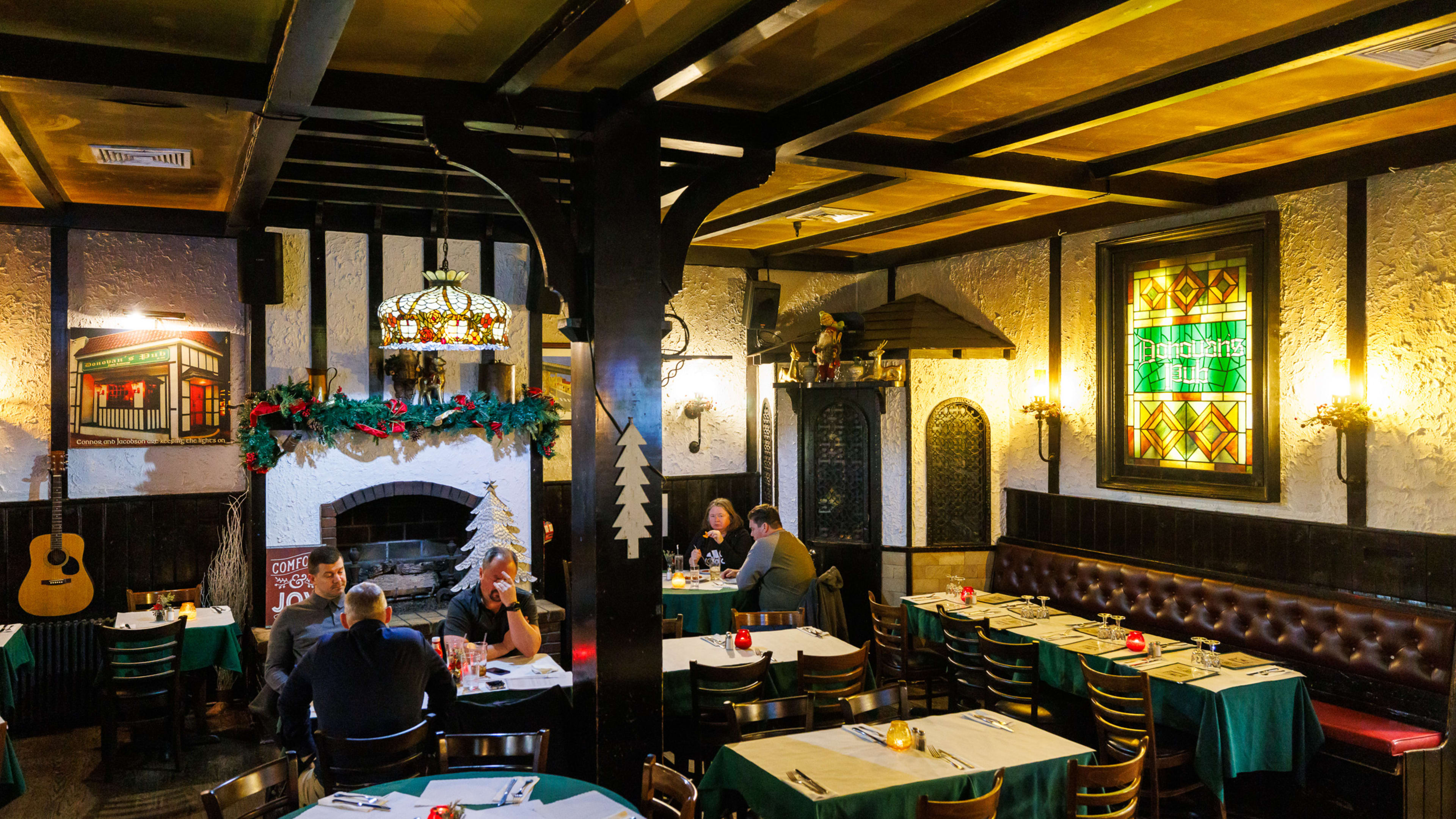 The dining area at Donovan's pub with tables, booths, and a fireplace with a guitar resting next to it.