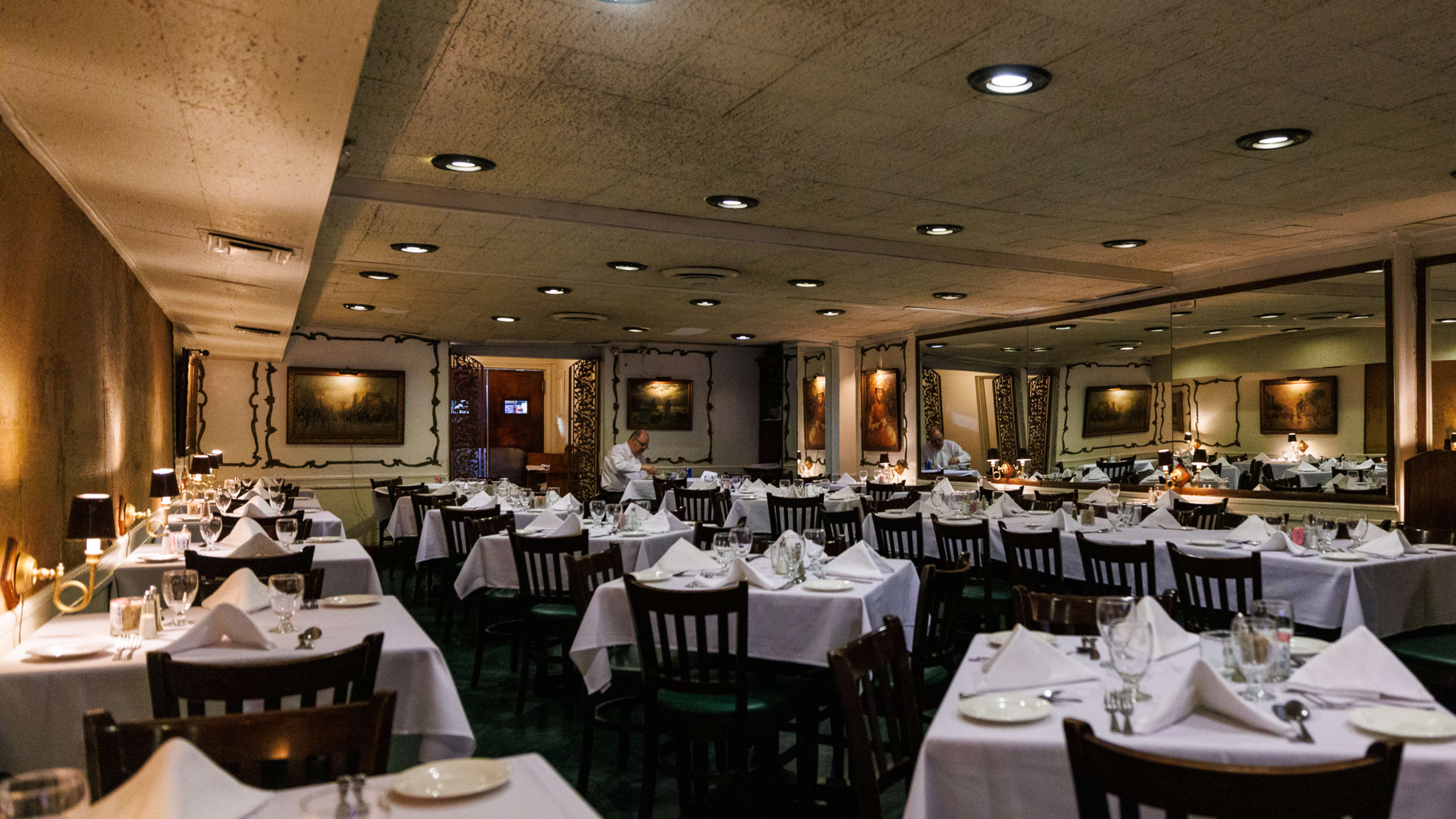 The dining room at Gene's with tables with white tablecloths and dark wooden chairs.