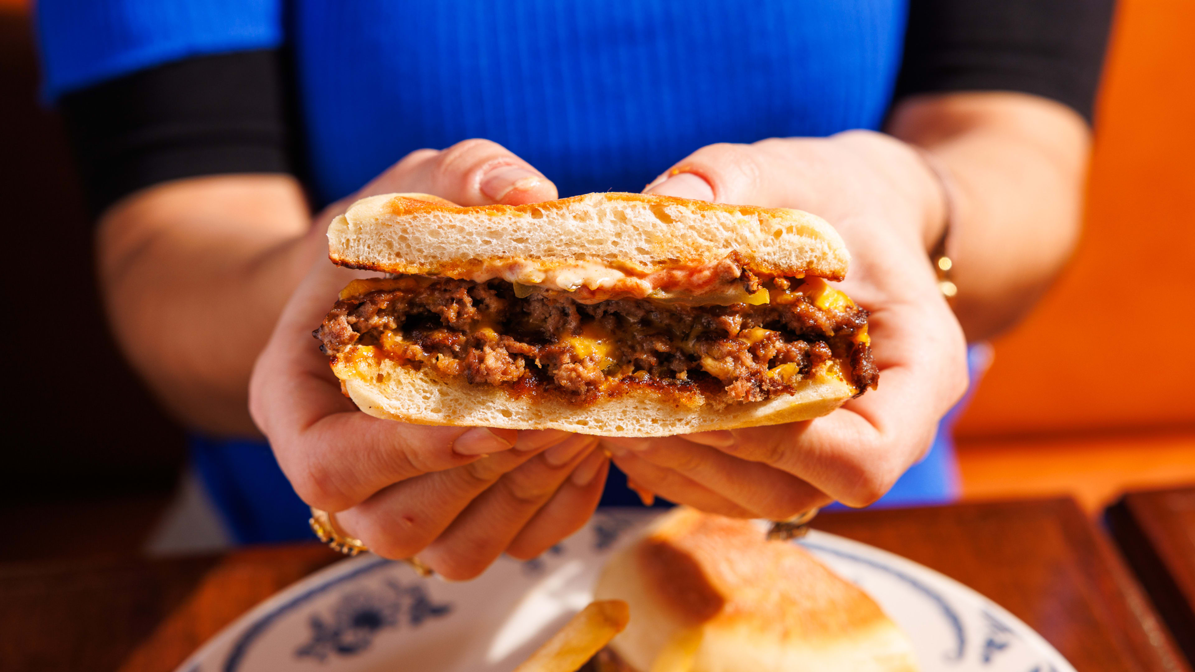 Hands holding half of a burger.