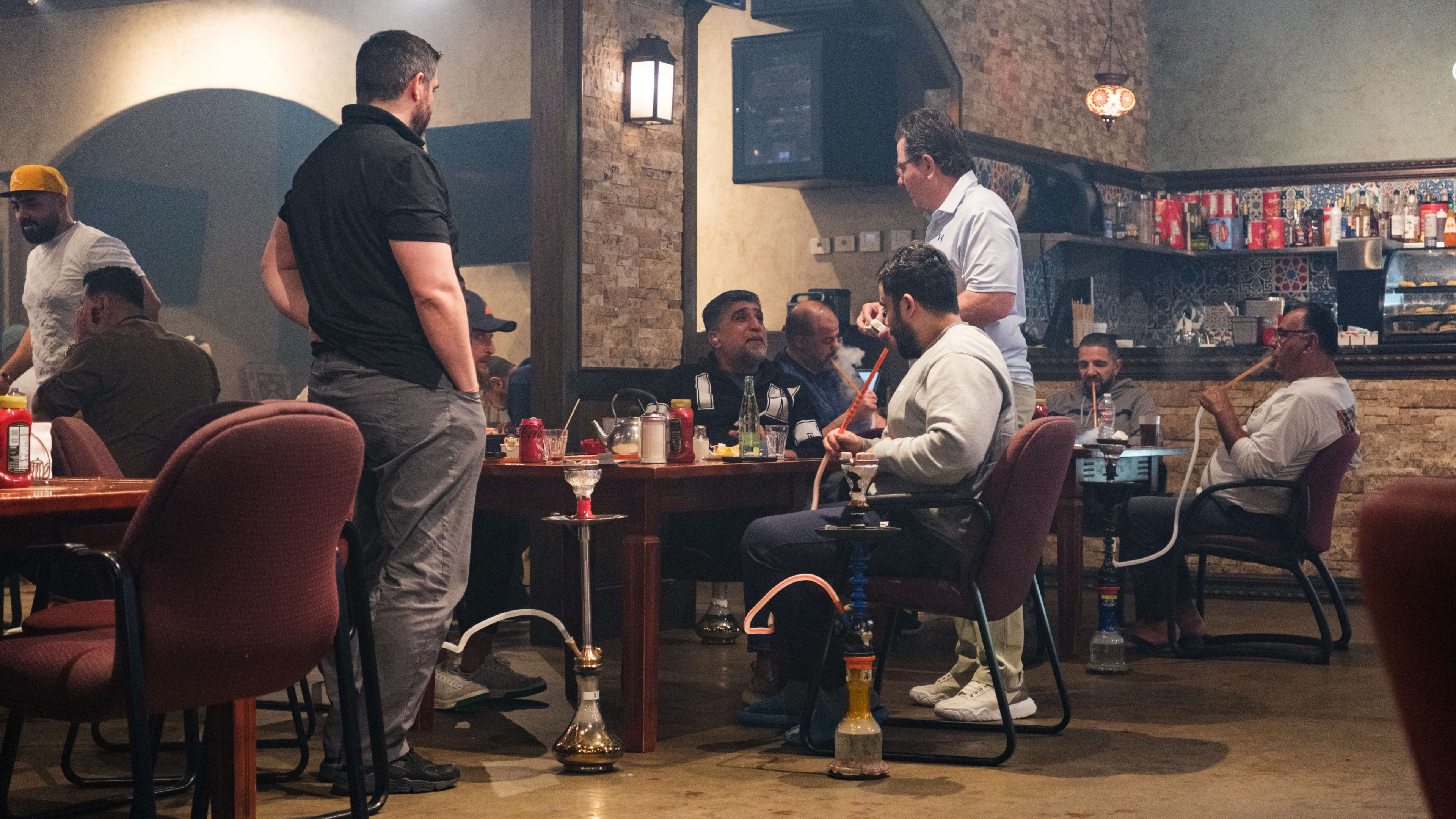 People sitting and standing around a table smoking hookah.