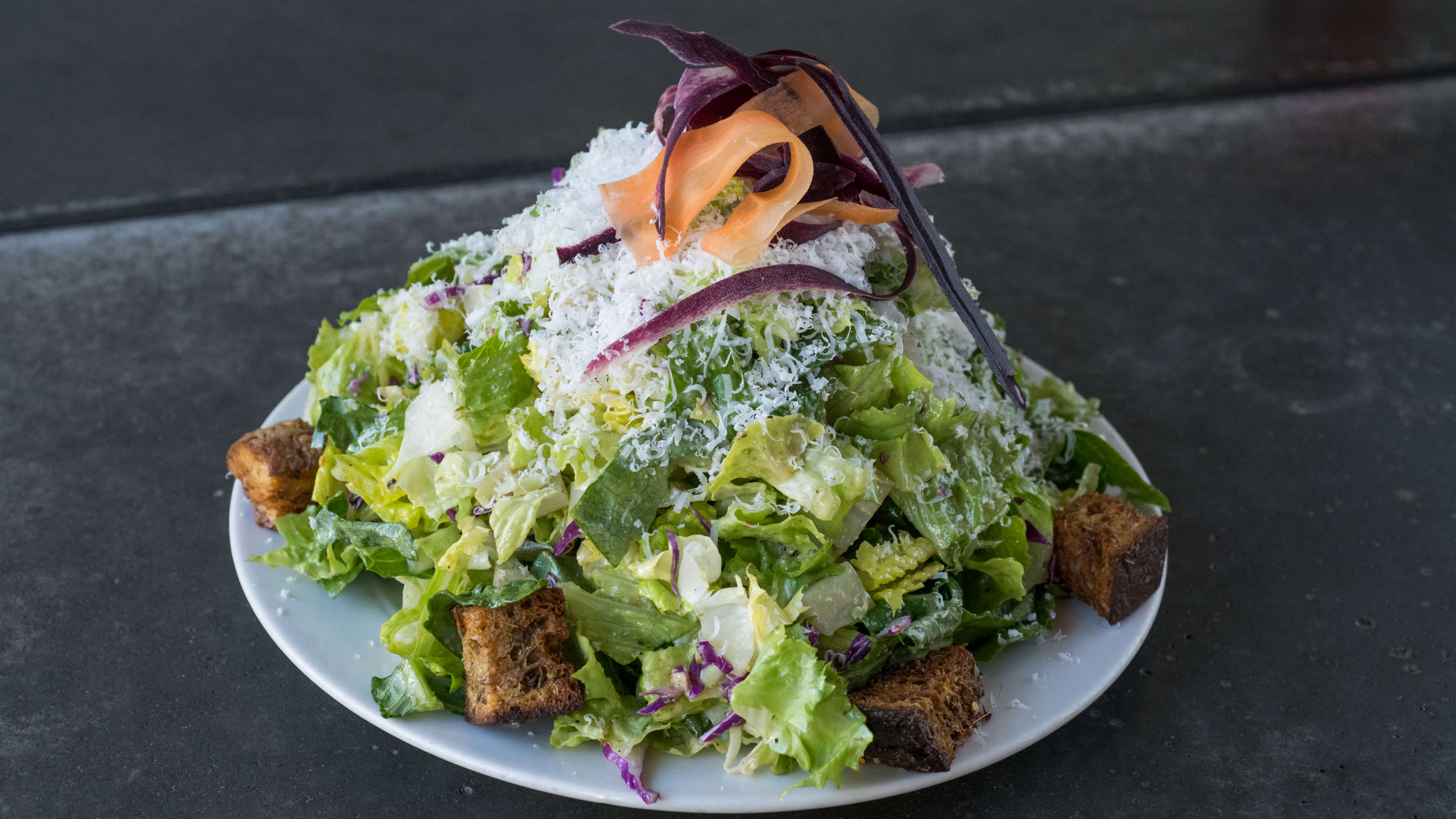 Plate heaped with romaine, croutons, and shaved parm.