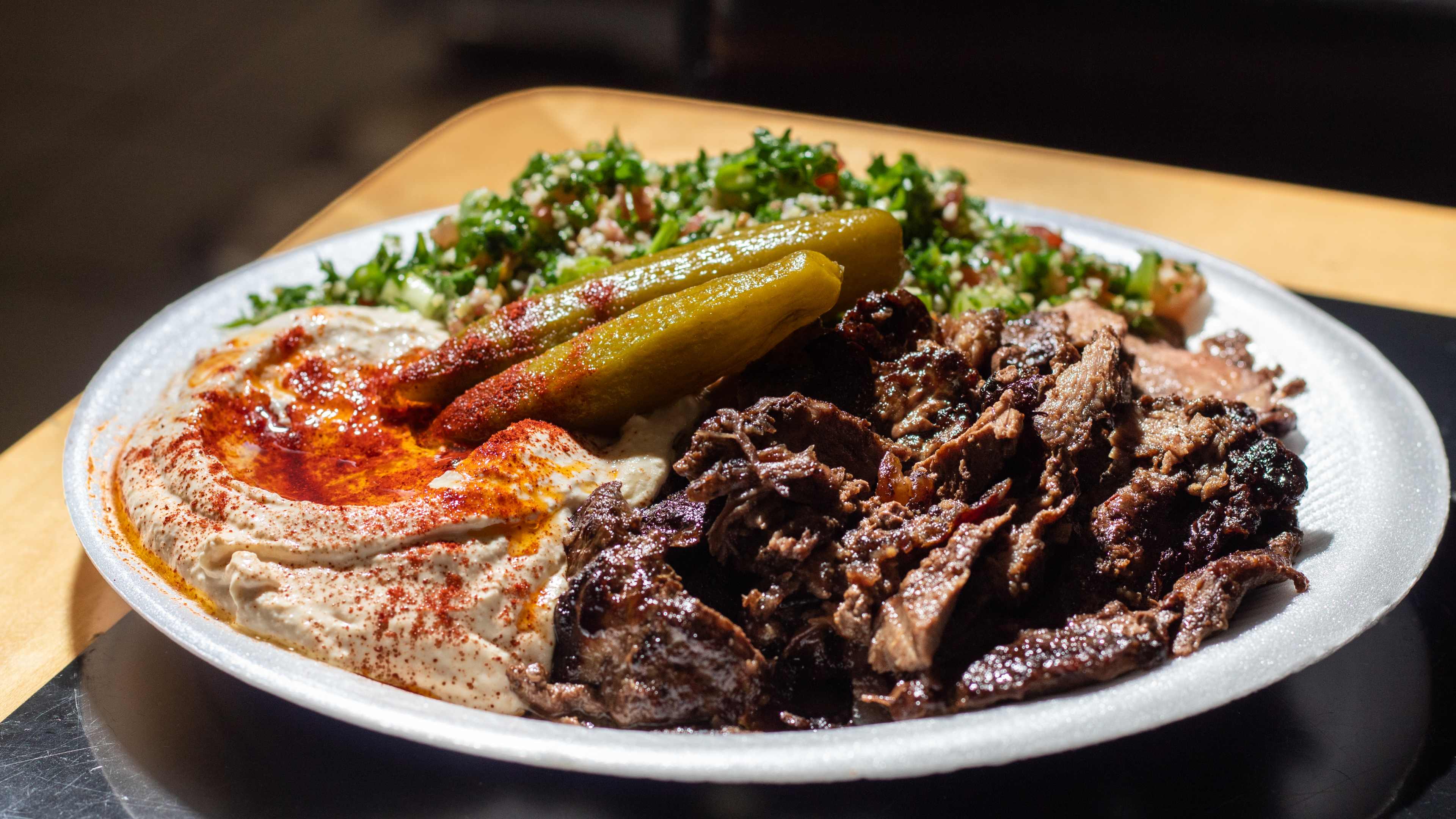 meat shawarma plate with silky, paprika-dusted hummus, pickles, and salad
