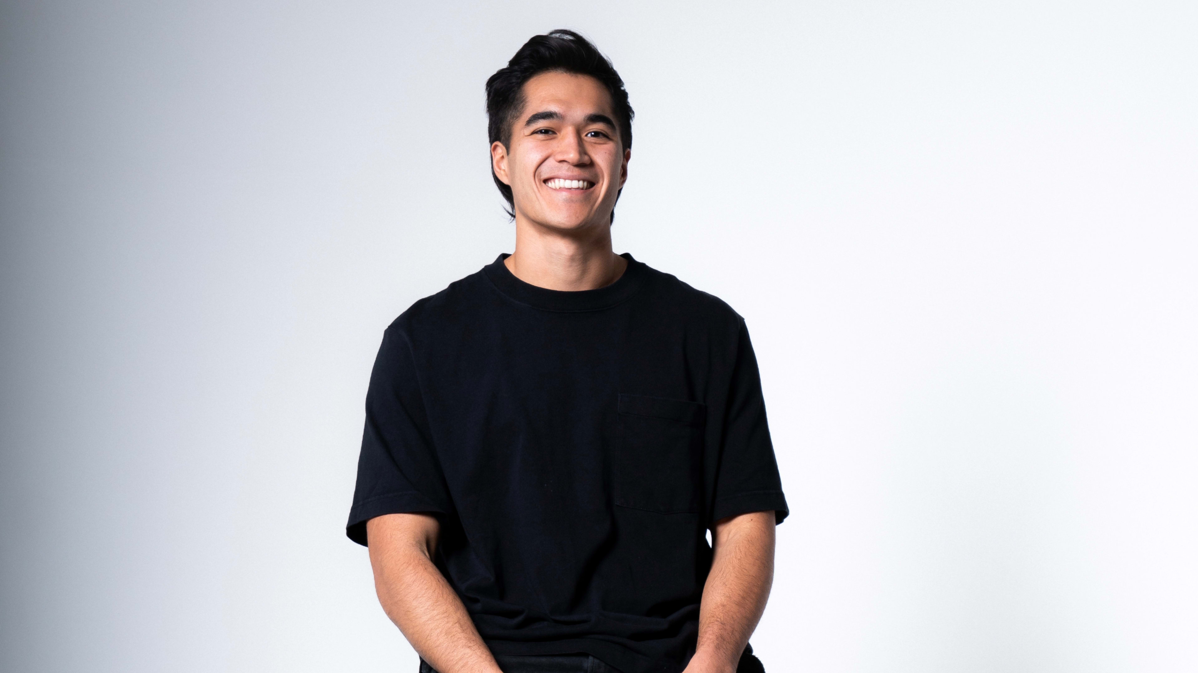 a photo of a man with slicked back hair in a black t-shirt