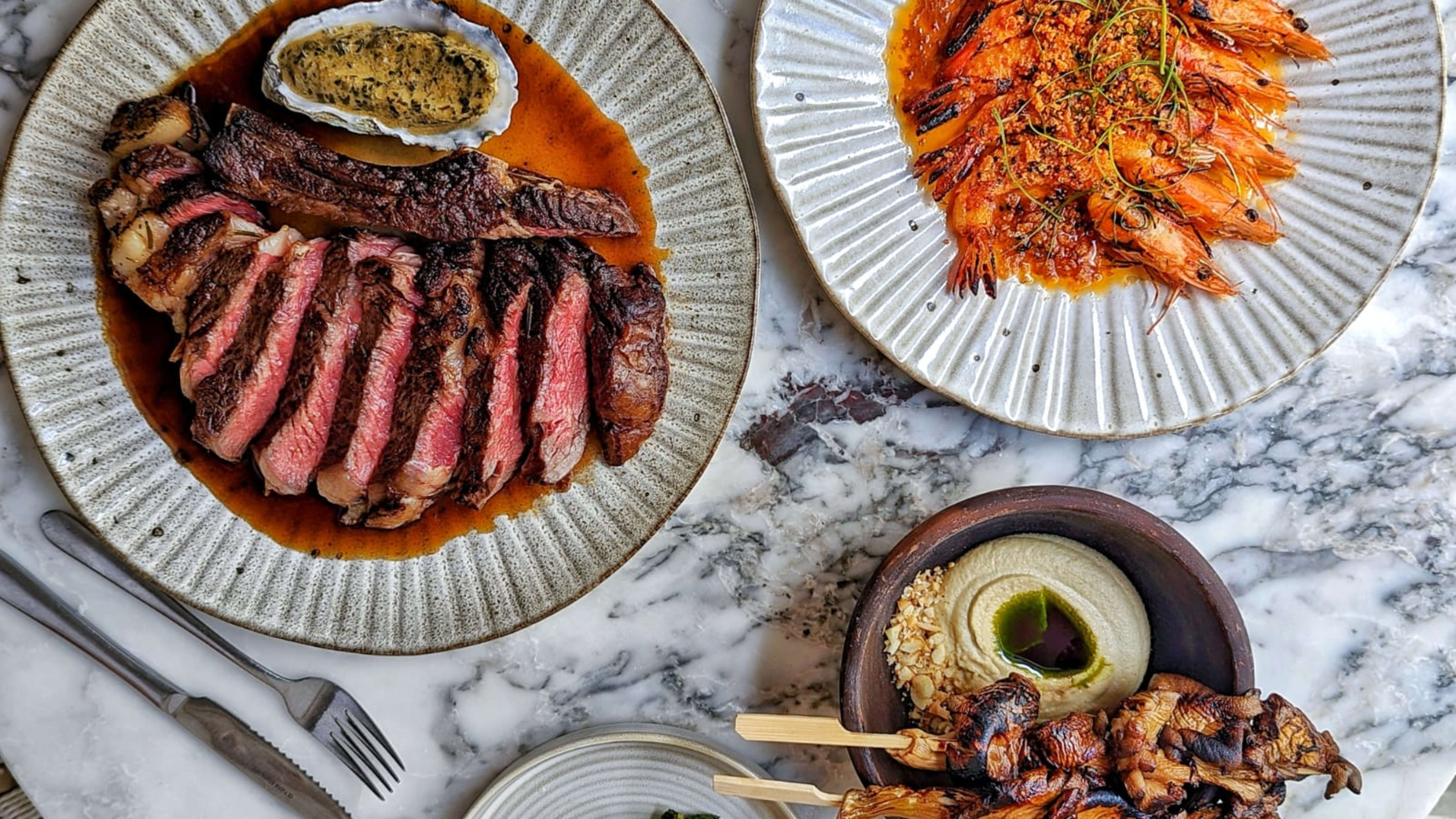 A food spread at Milk Beach in Soho, including a steak.