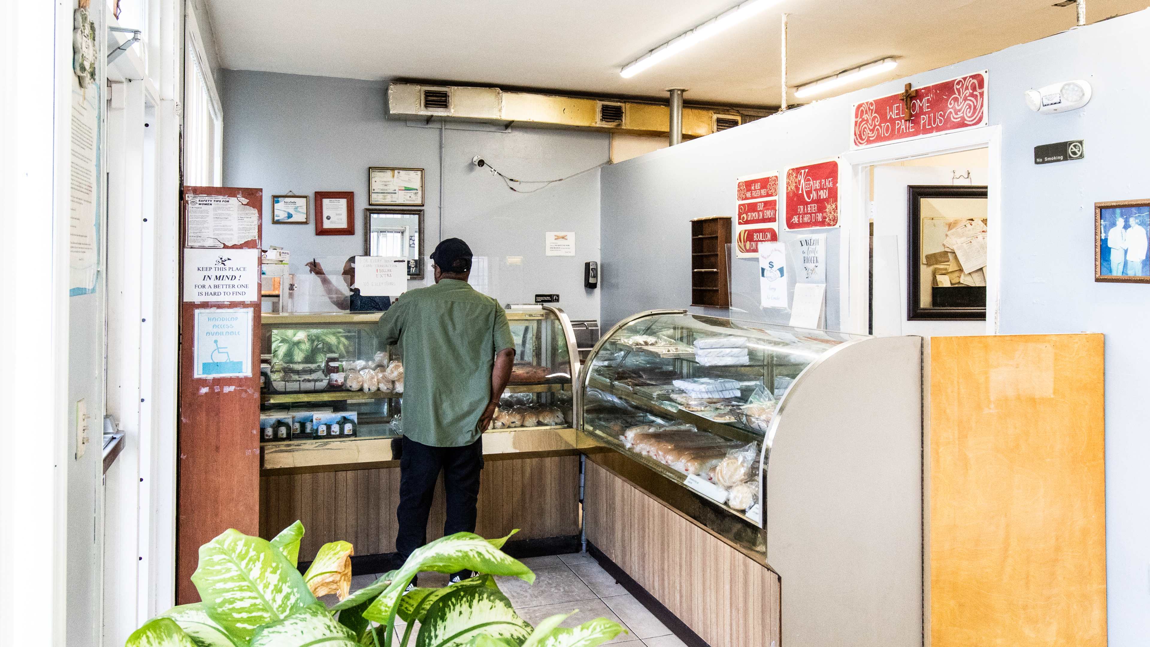A man orders at a counter inside a small bakery.