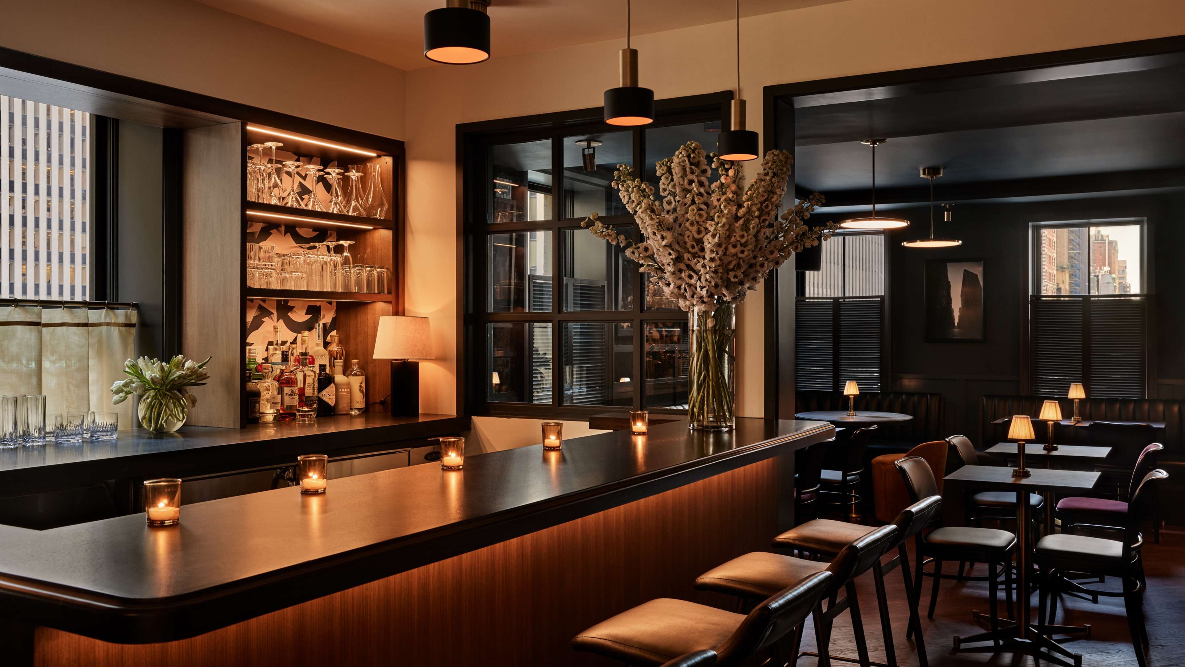 The bar on the third floor at Pebble Bar, which is lines with votive candles and leather barstools. There are two top tables in the back.