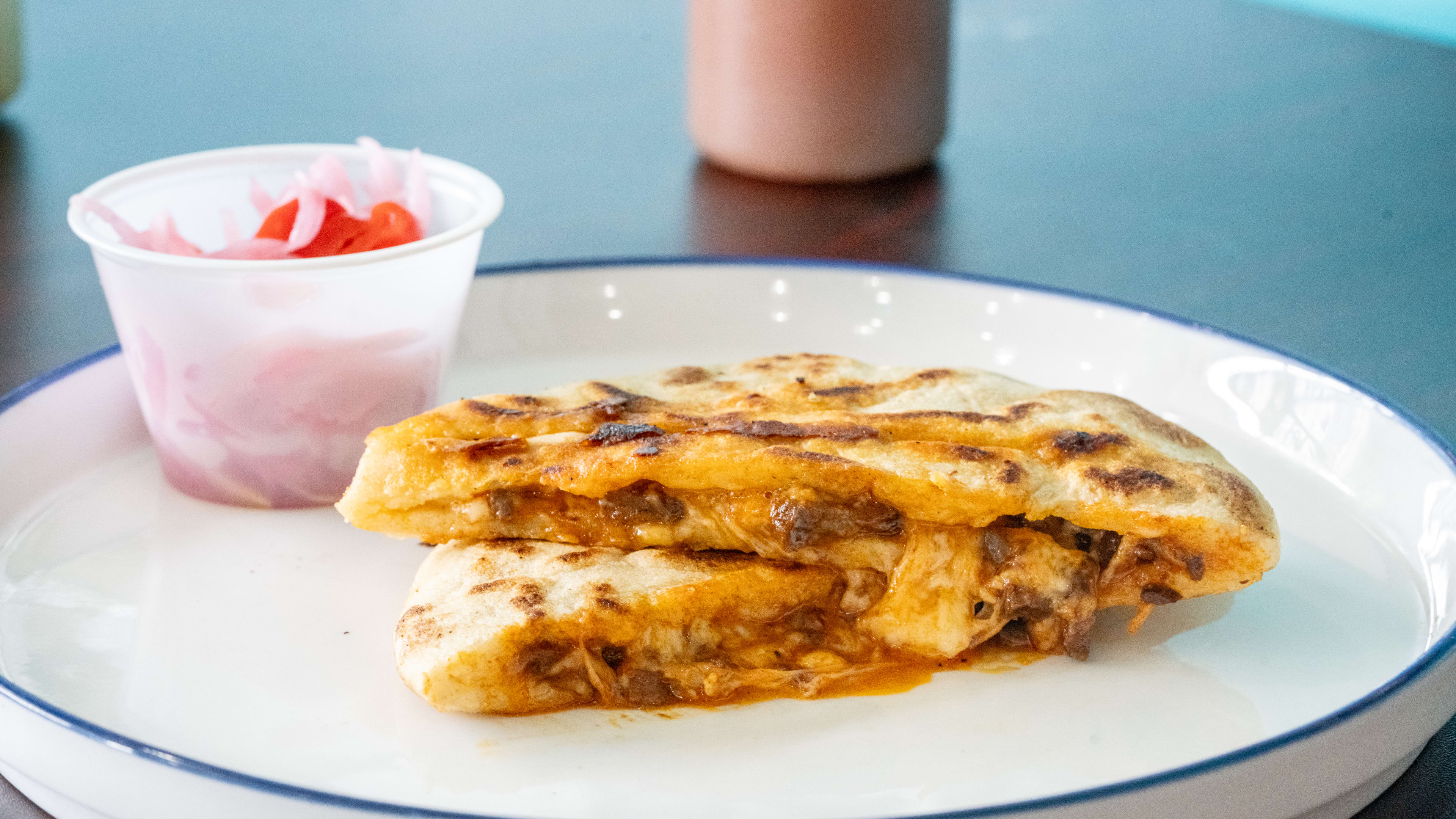 A pupusa cut in half on a plate.