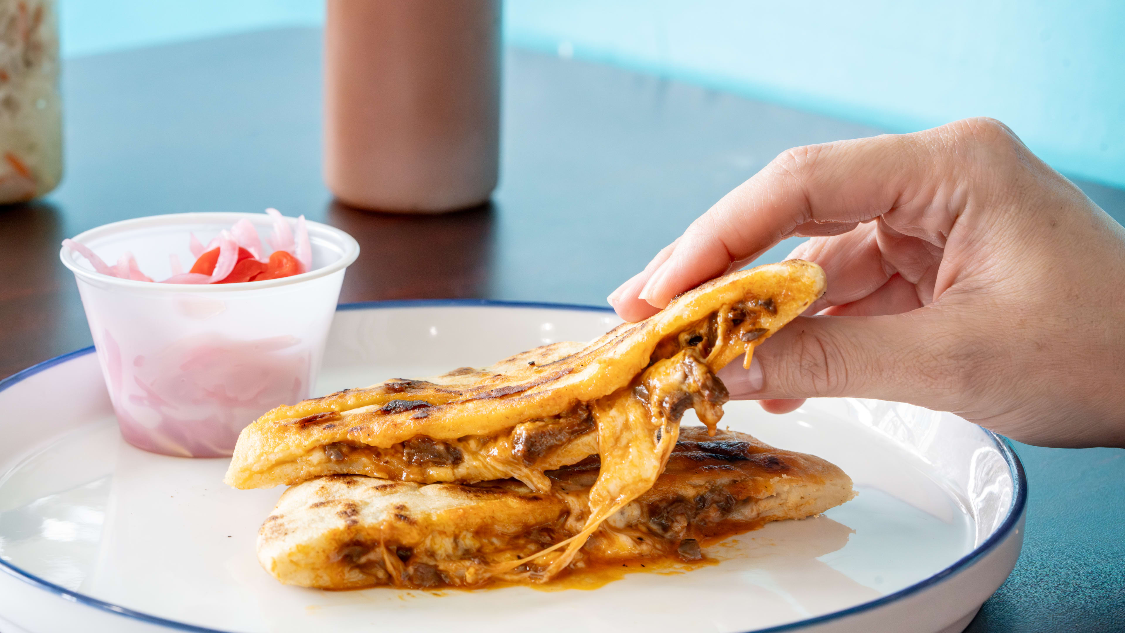 cheesy pupusa with meat served next to pickled onion