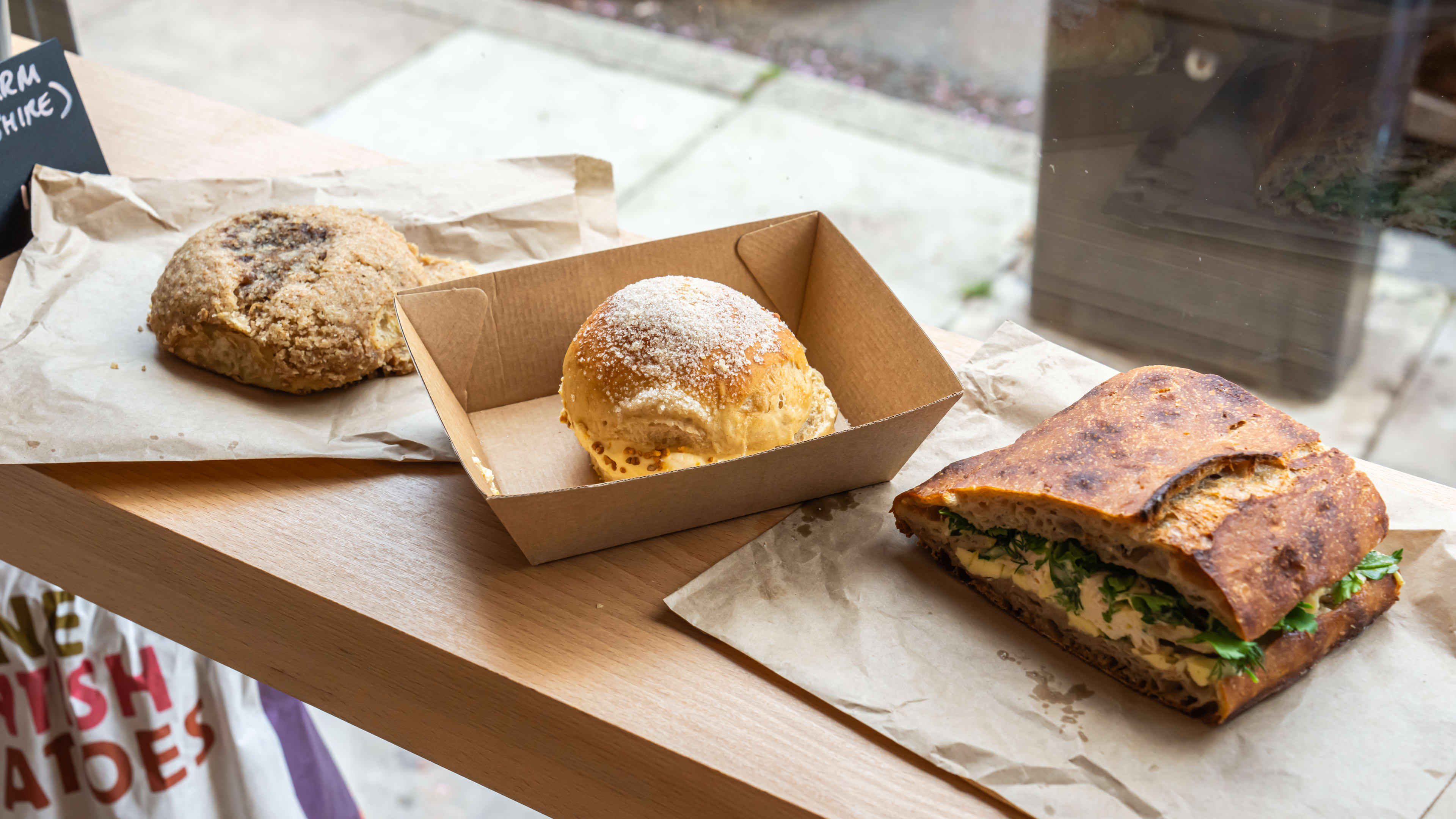 Two buns and a sandwich on the window counter at Quince Bakery