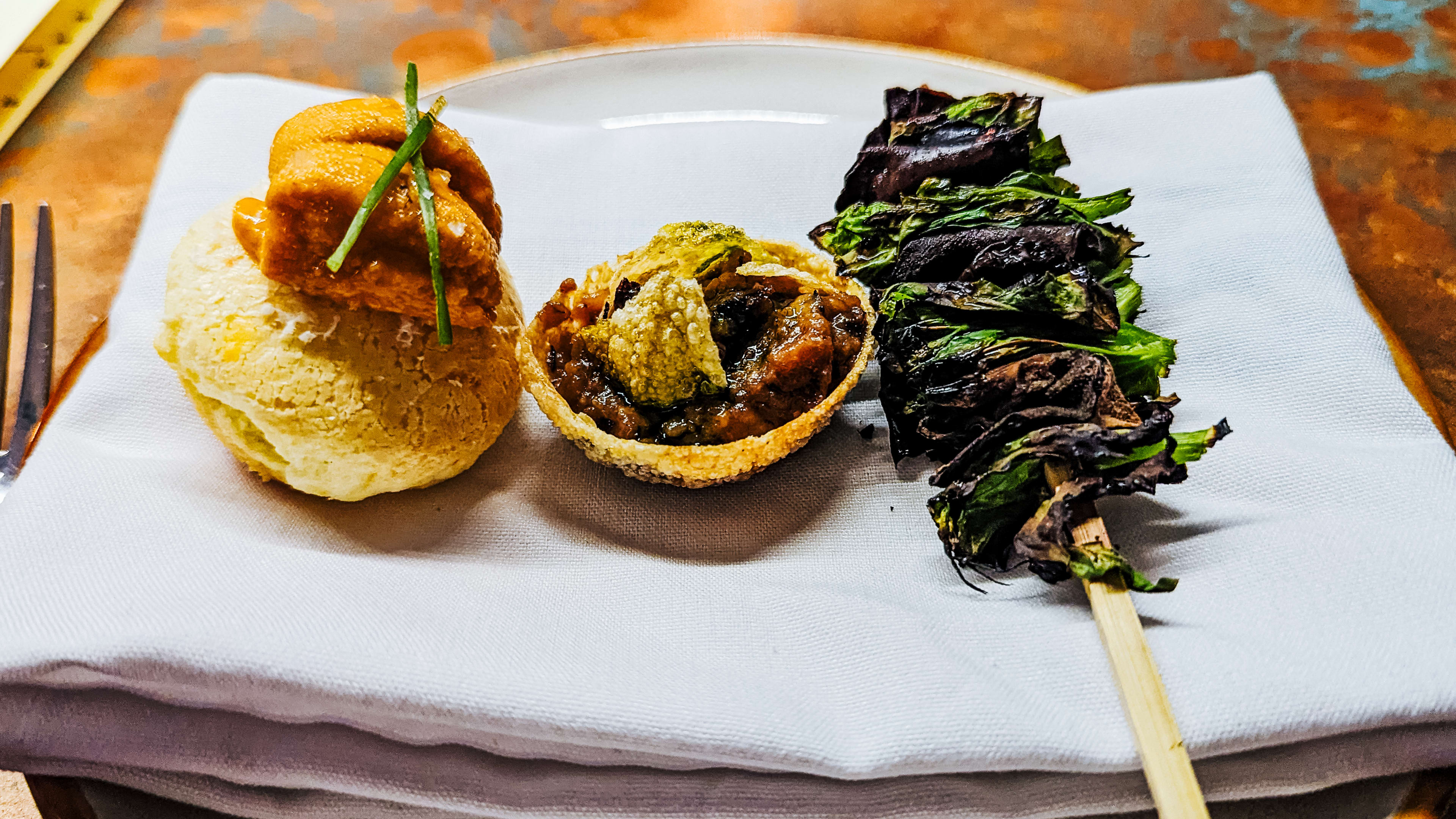 Small bites at Ramro's tasting menu, including uni mochi puff, bharta on pain puri, and a skewer of pea shoots.