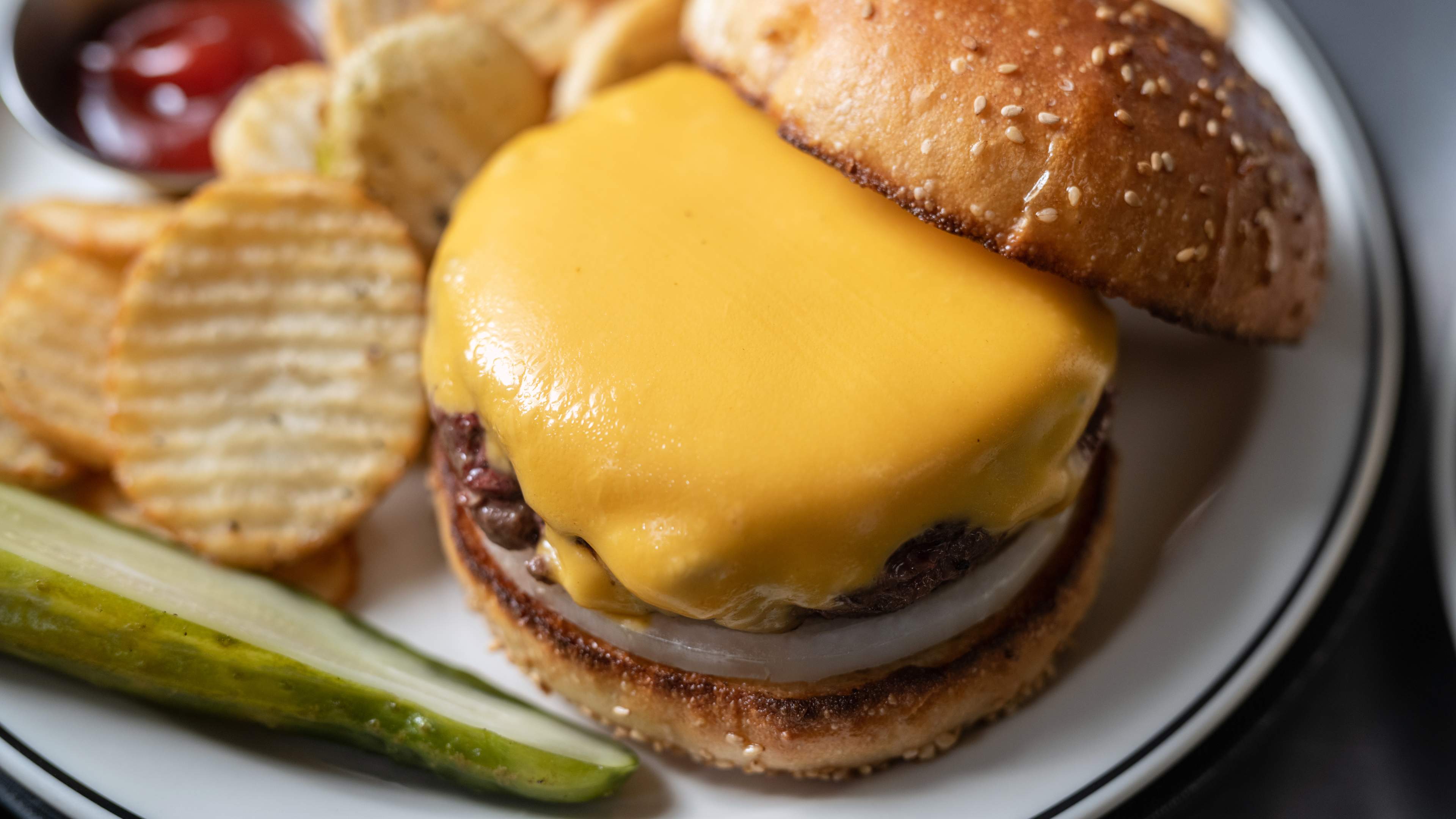 a burger with cottage fries and a pickle spear