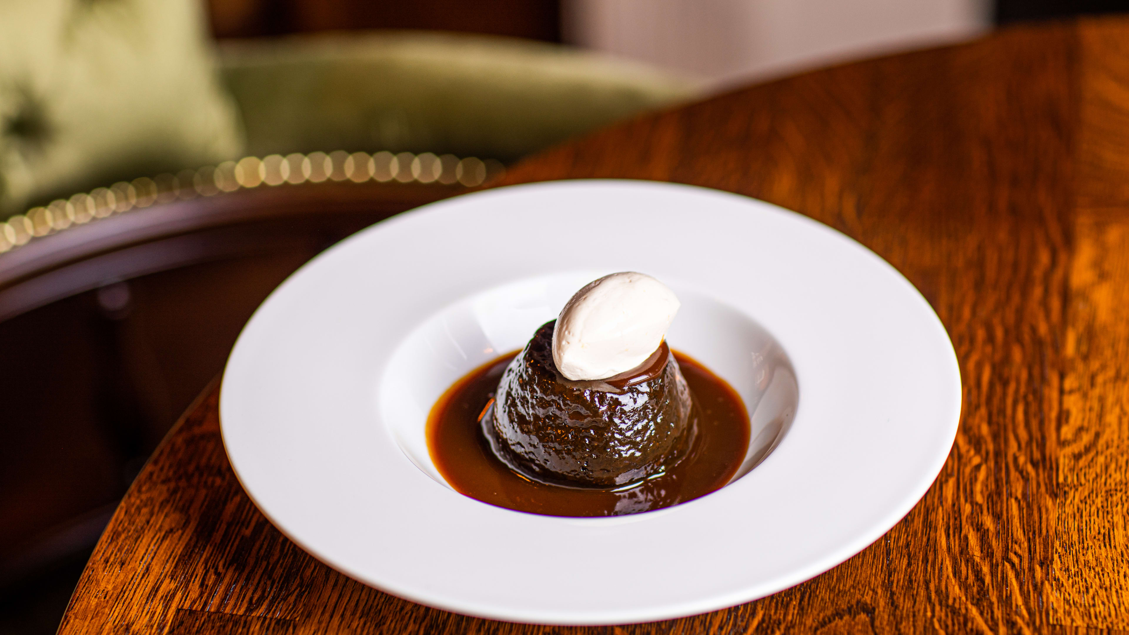 A sticky toffee pudding with a quenelle of cream on top.