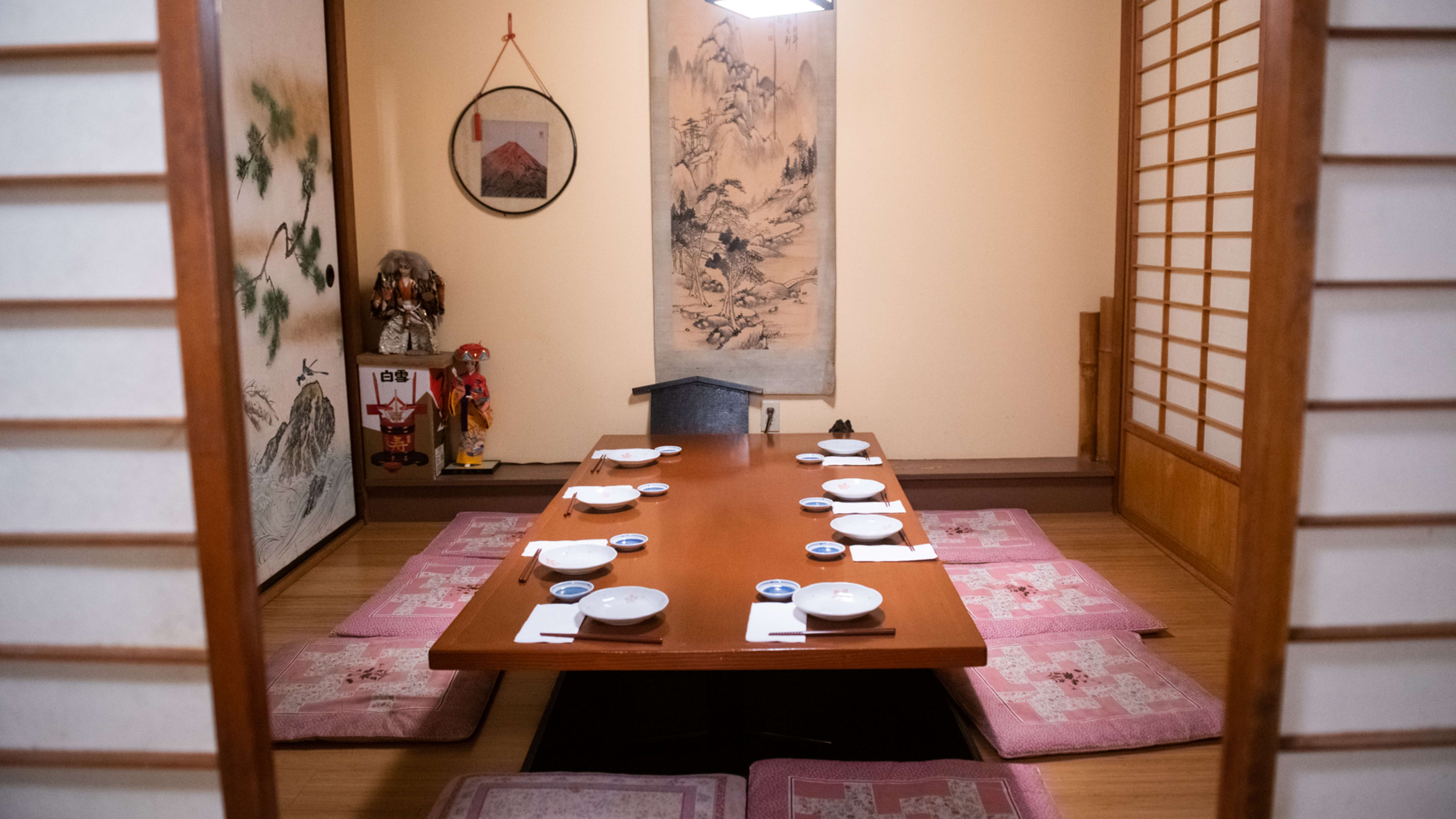 Private room interior with low table, seating mats, and decorated in traditional Japanese art.