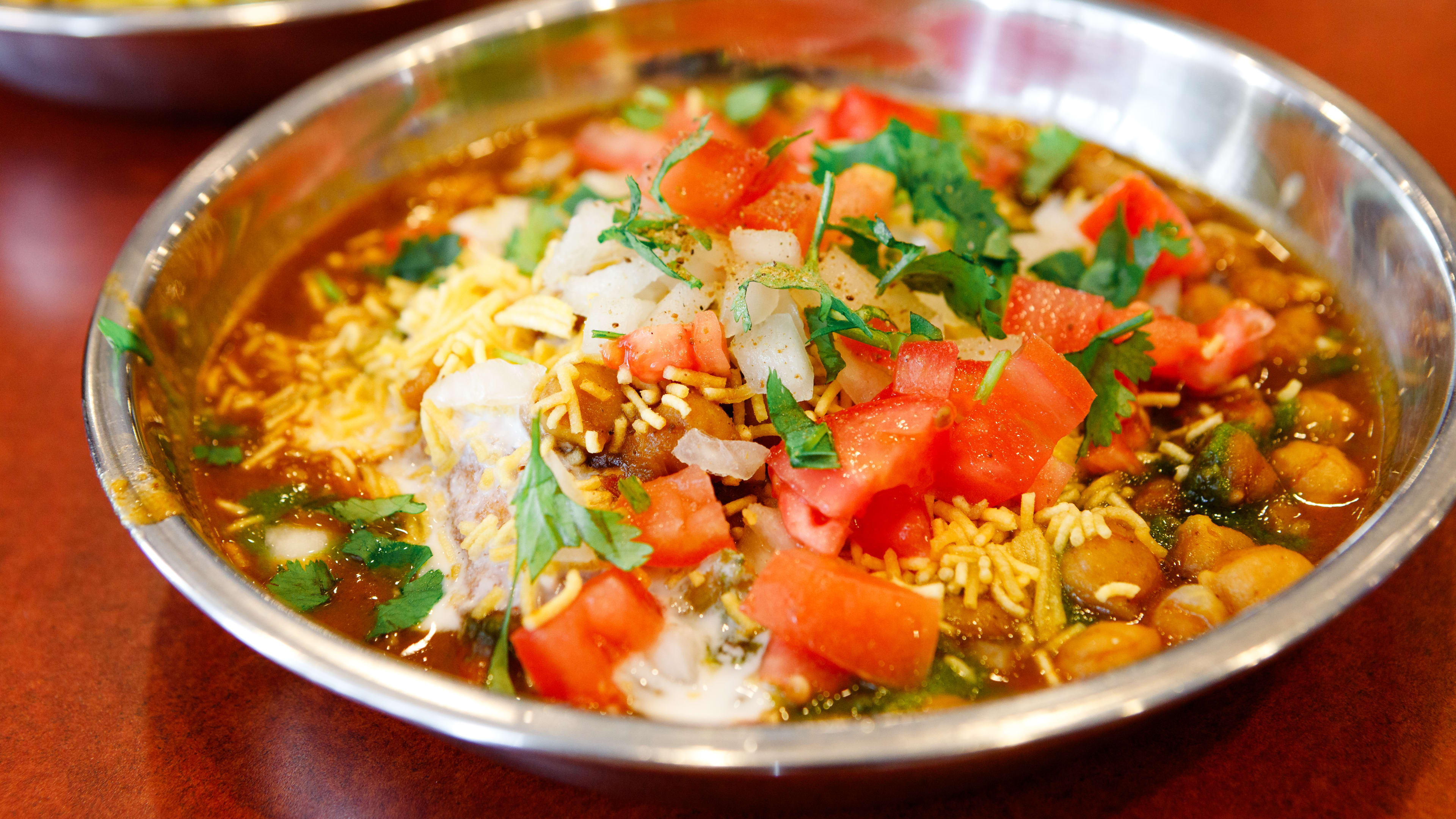 A metal bowl of samosa chaat from Shri Balaji Bhavan.