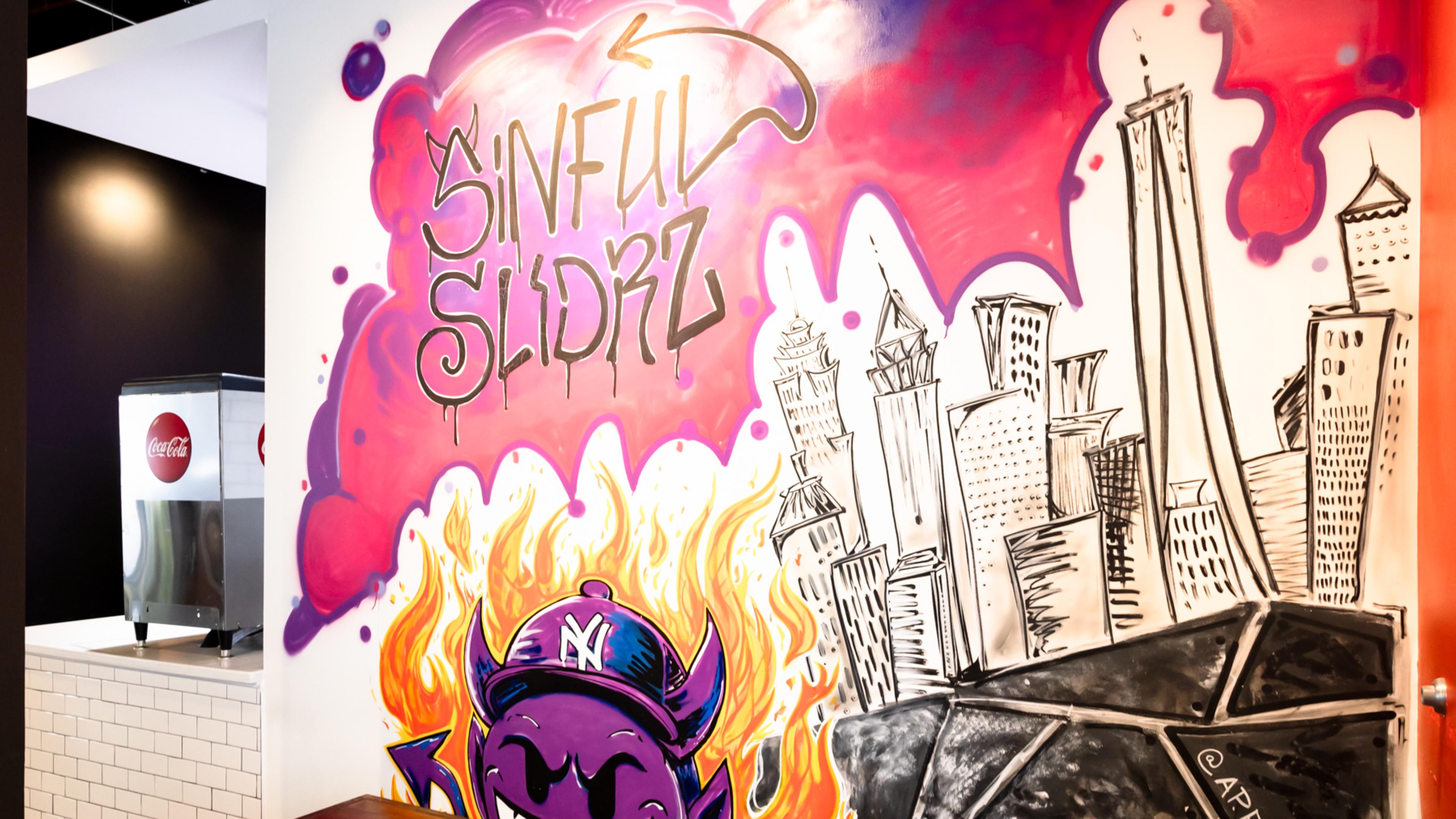 Sinful Slidrz mural with a skyline and devil emoji.