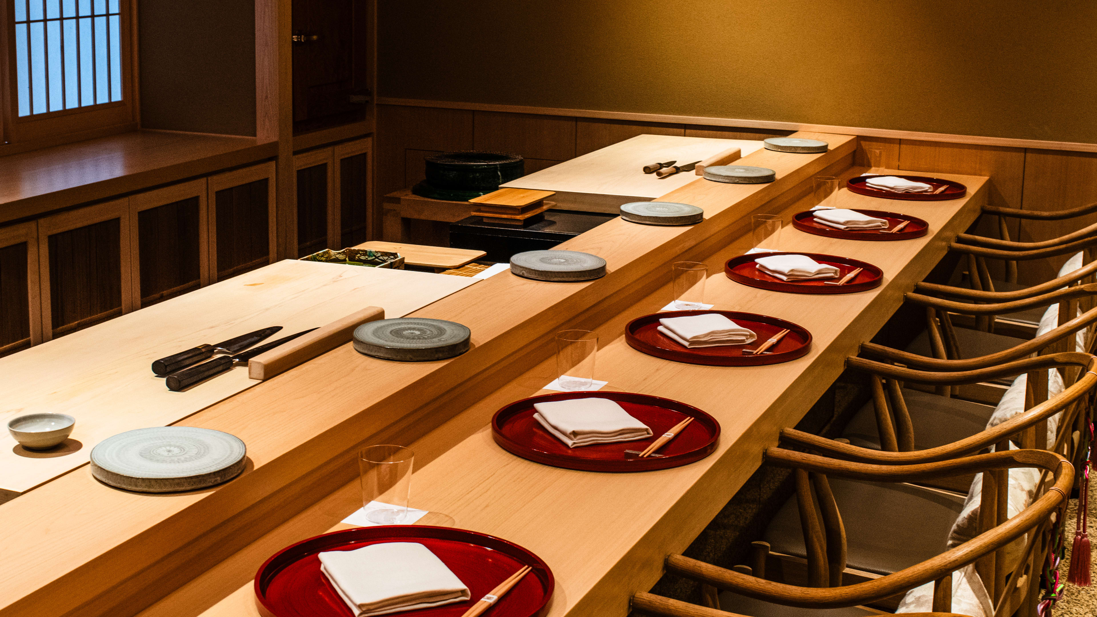 The counter set-up at Sushi Kanesaka. There are red ceramic plates and a small blue ceramic plate at the upper level, where sushi is placed.