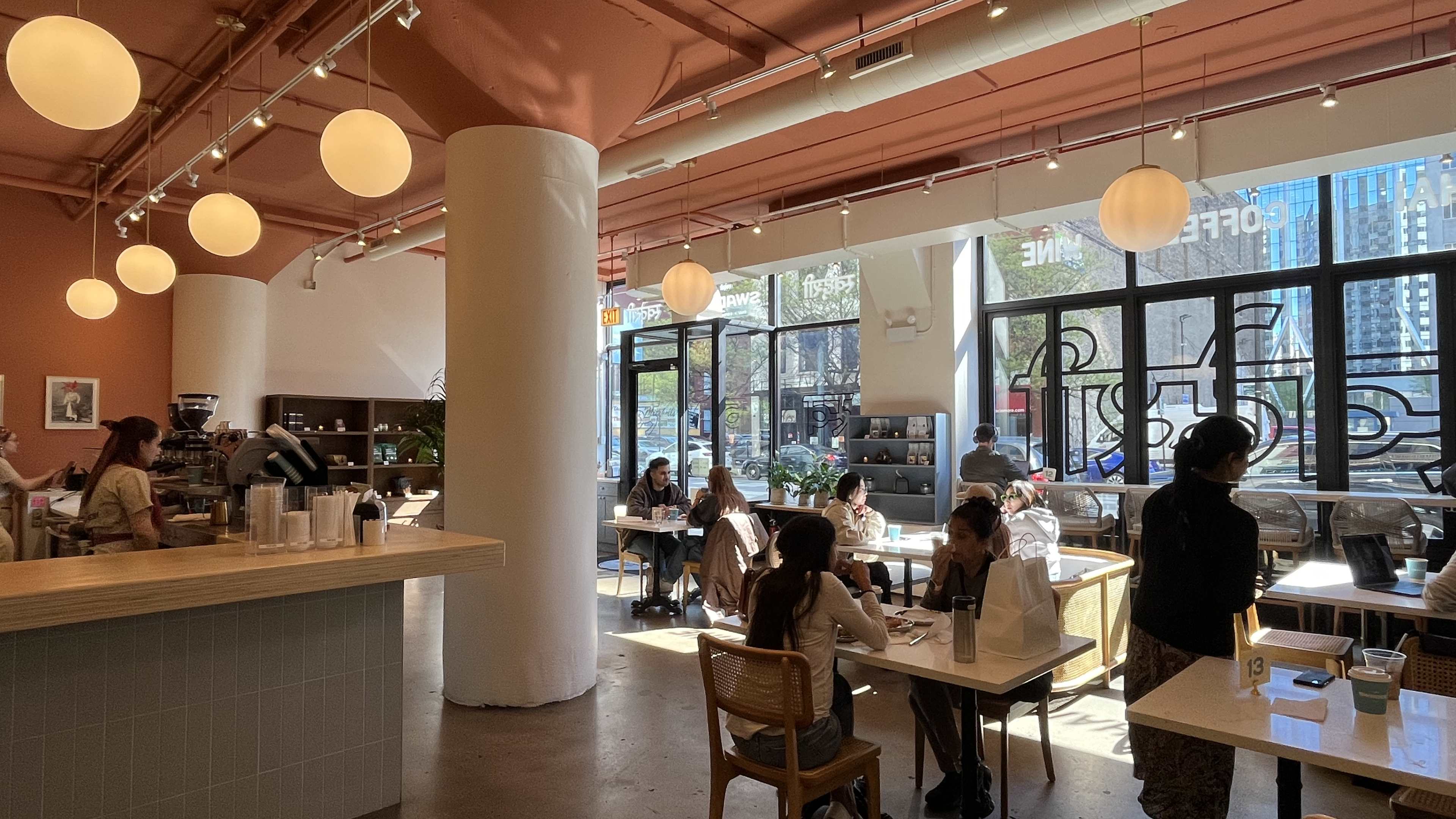 Bright, modern interior of Swadesi coffee shop with big windows, lots of tables, and high ceilings