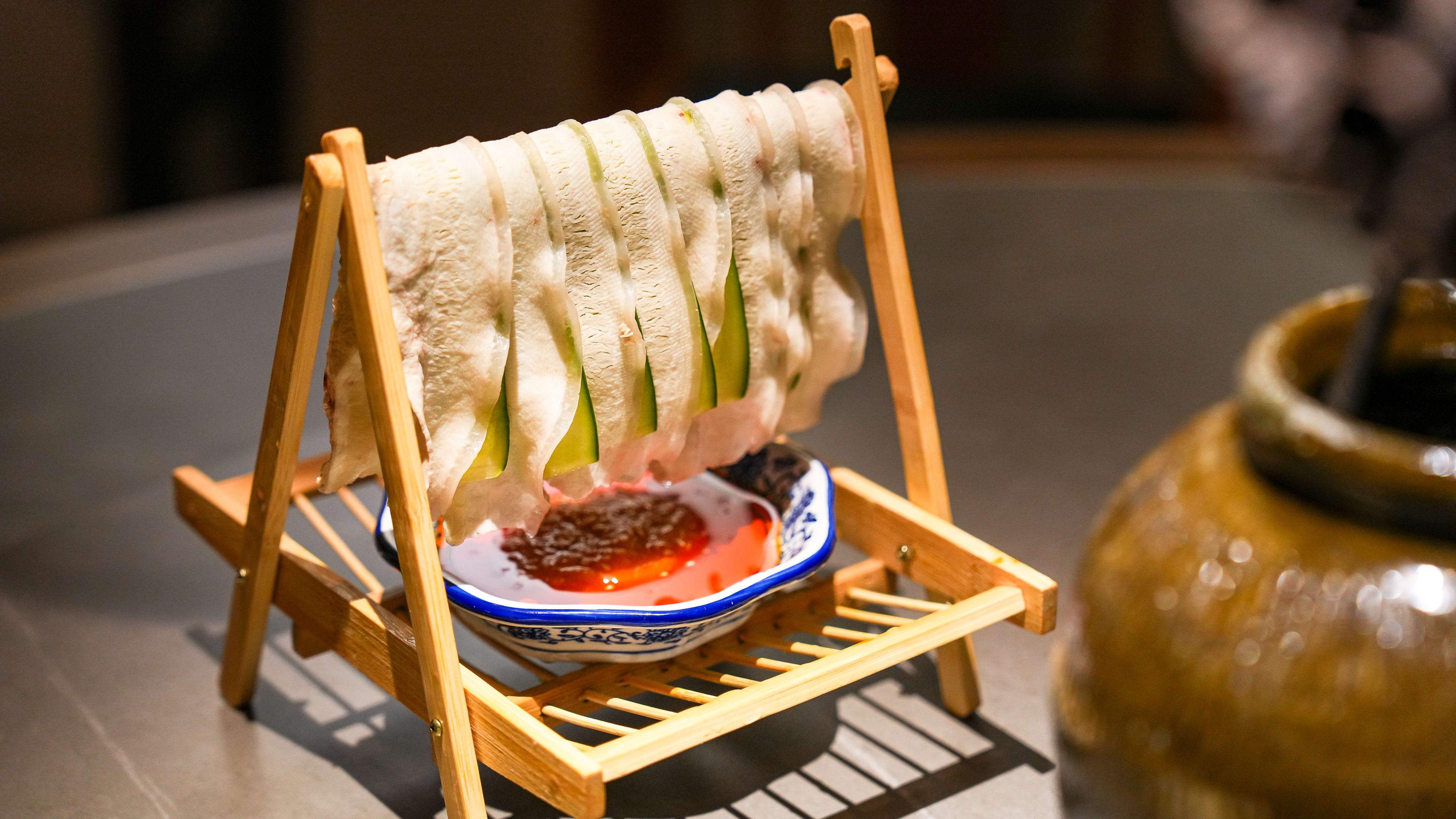 Swing pork belly with slivers of cucumber hung on wooden stand at Szechuan Mountain House