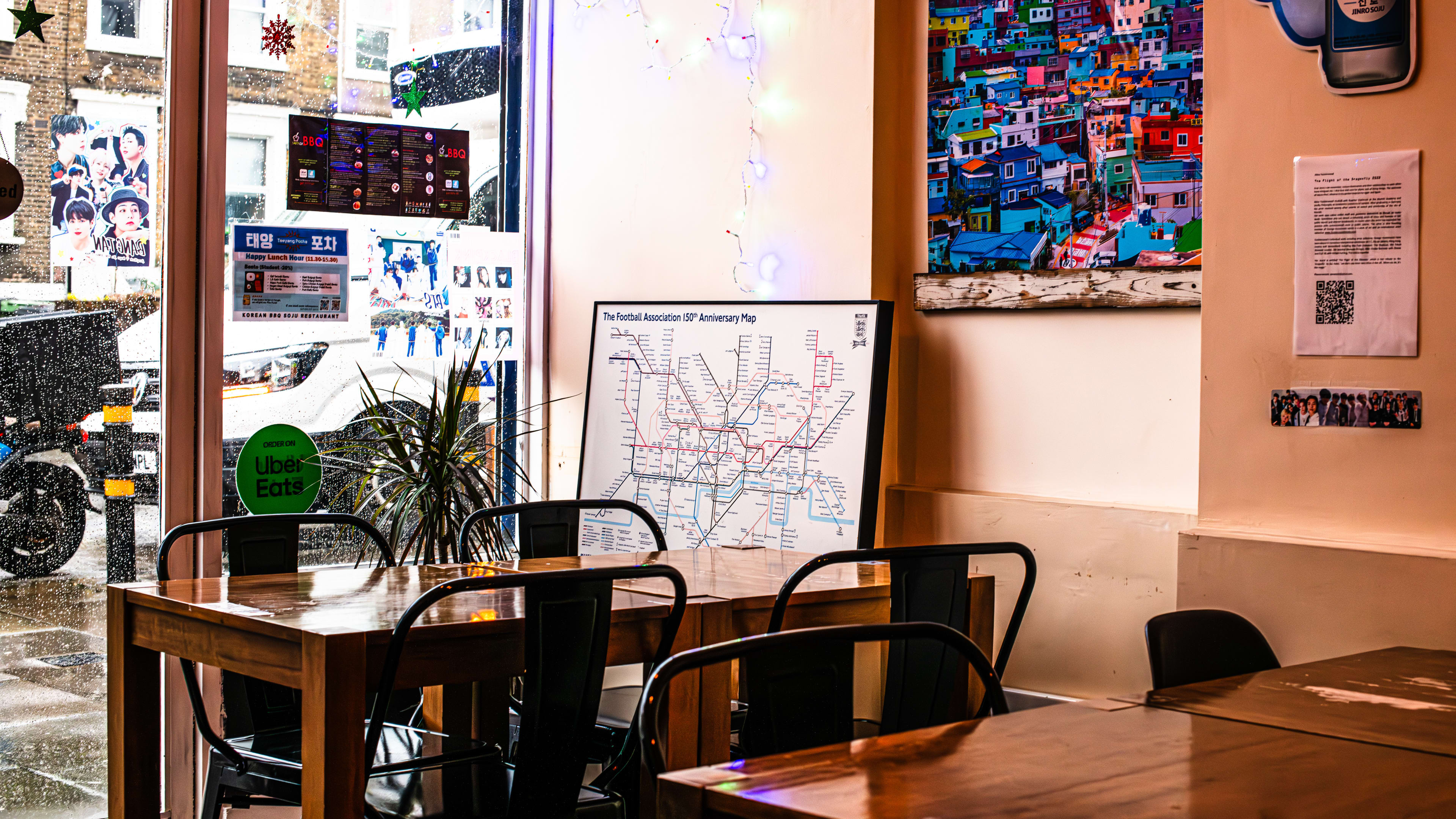 Interior of Taeyang Pocha with wooden tables, metal chairs, and art depicting maps on the wall