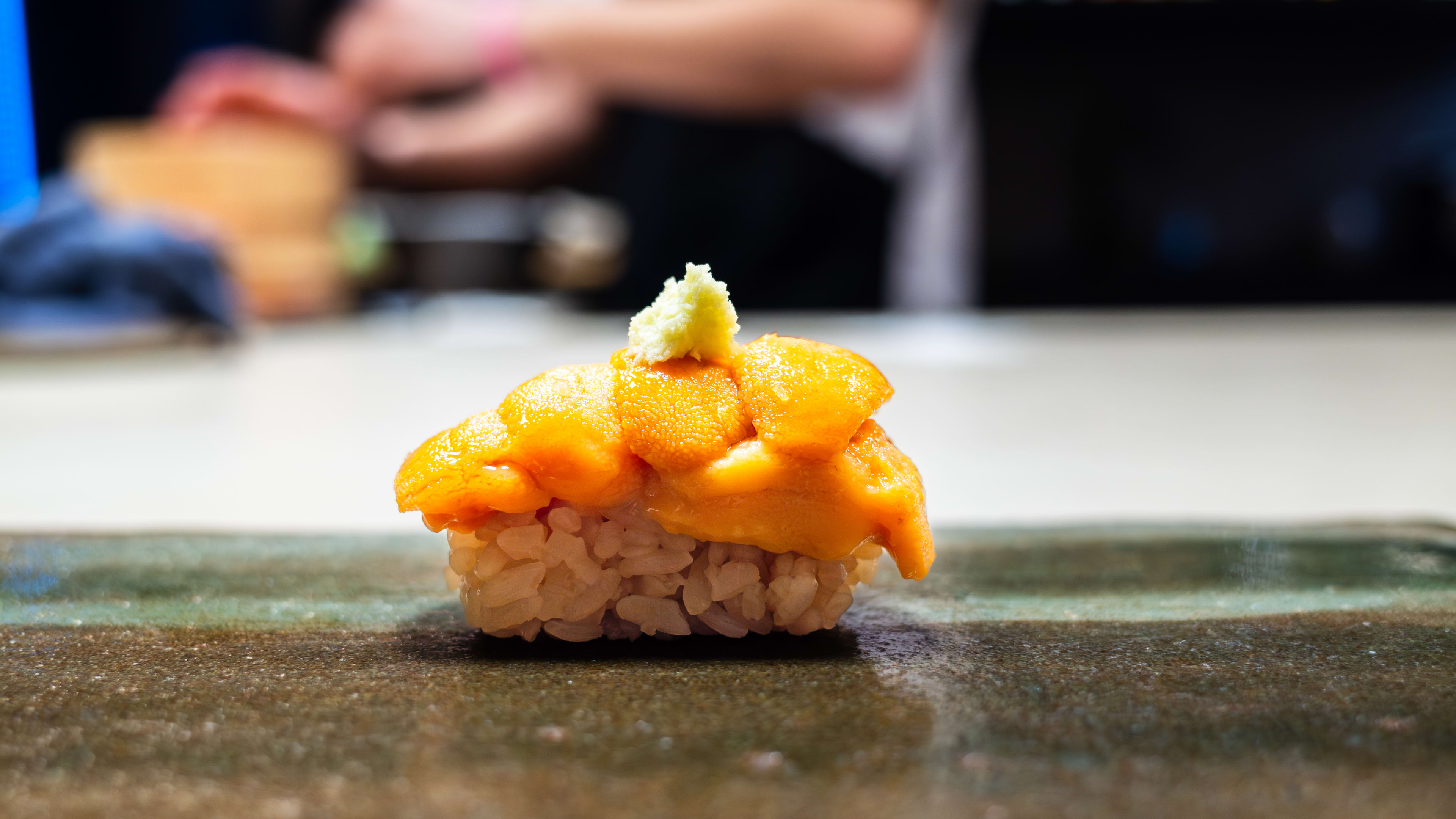 A piece of nigiri with uni and wasabi