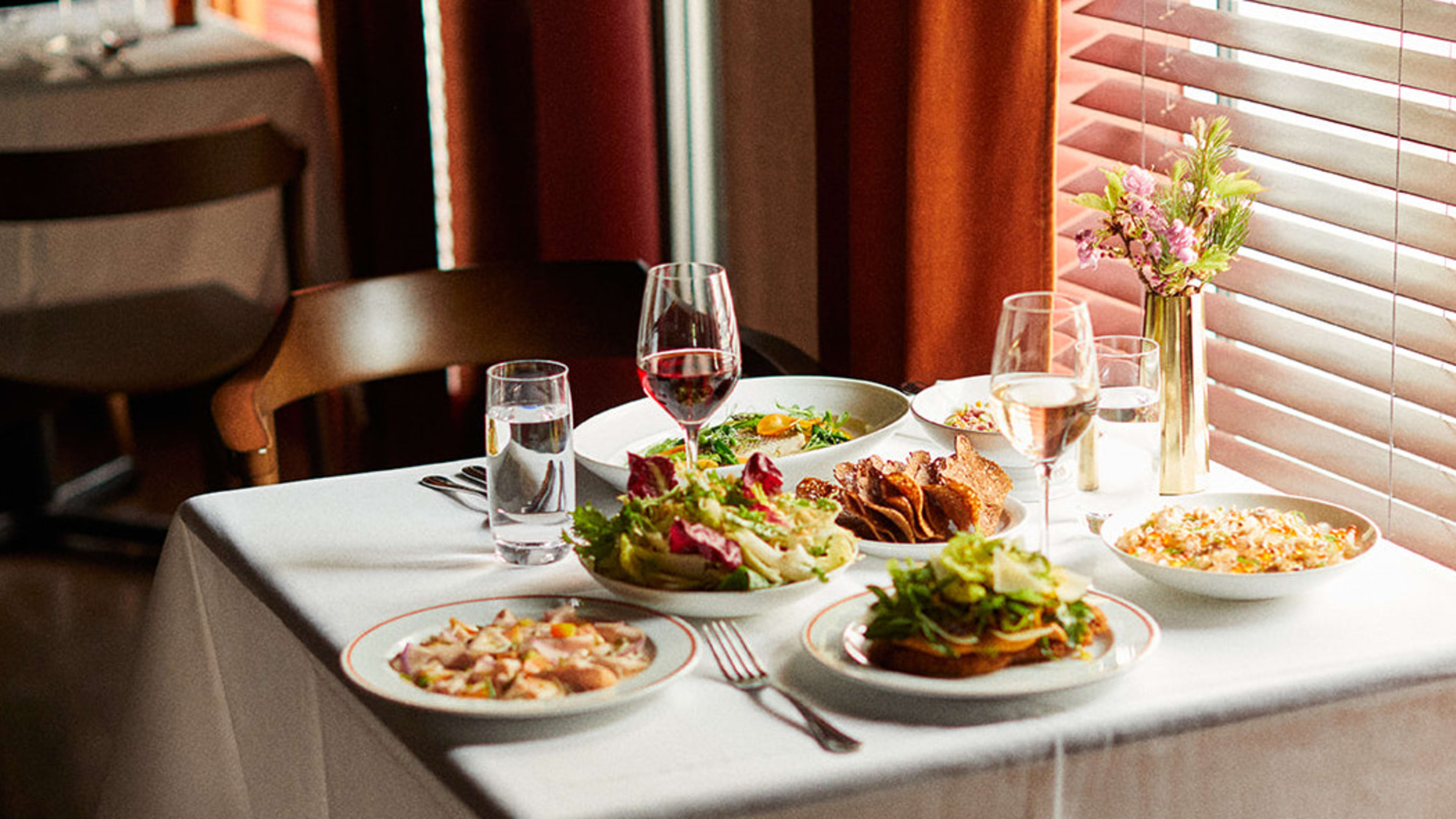 Spread of food and wine on low-lit table near the window at Fig