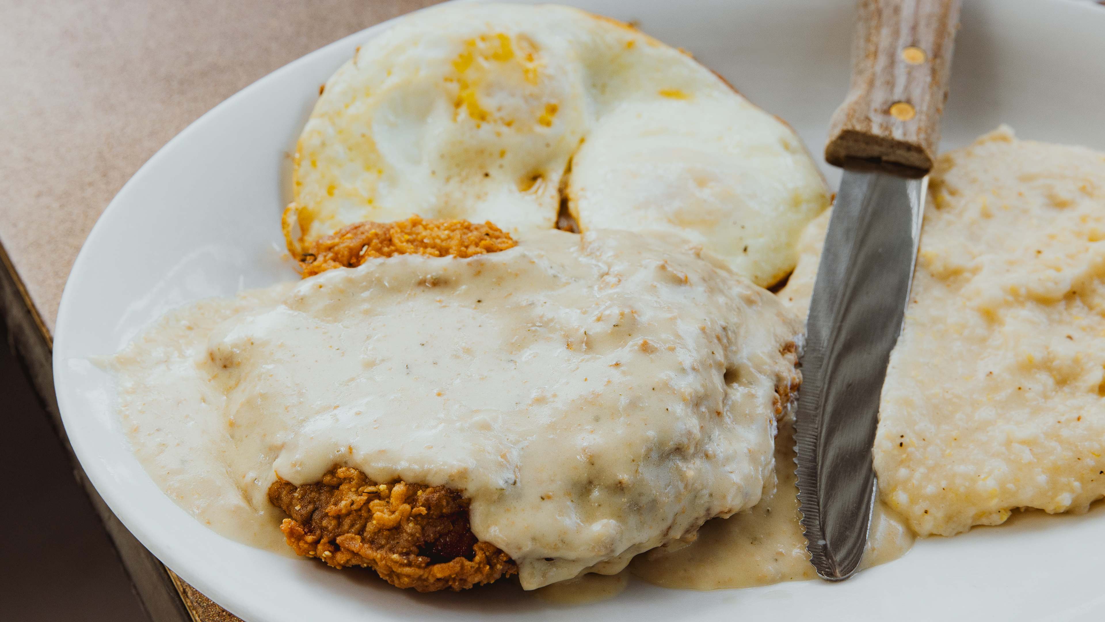 chicken fried steak with grits and fried eggs