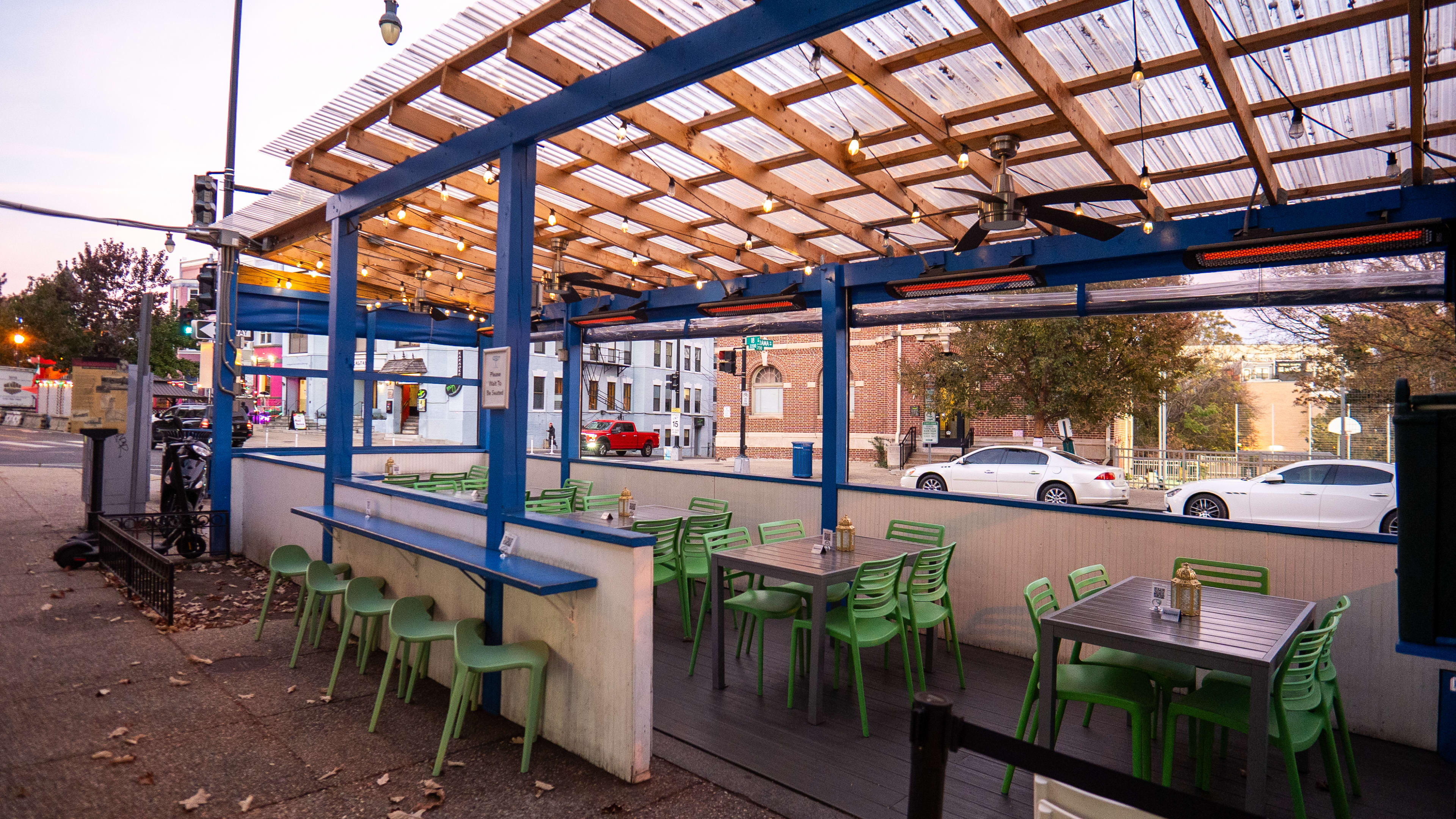 Dusky outdoor heated patio with tables and chairs.