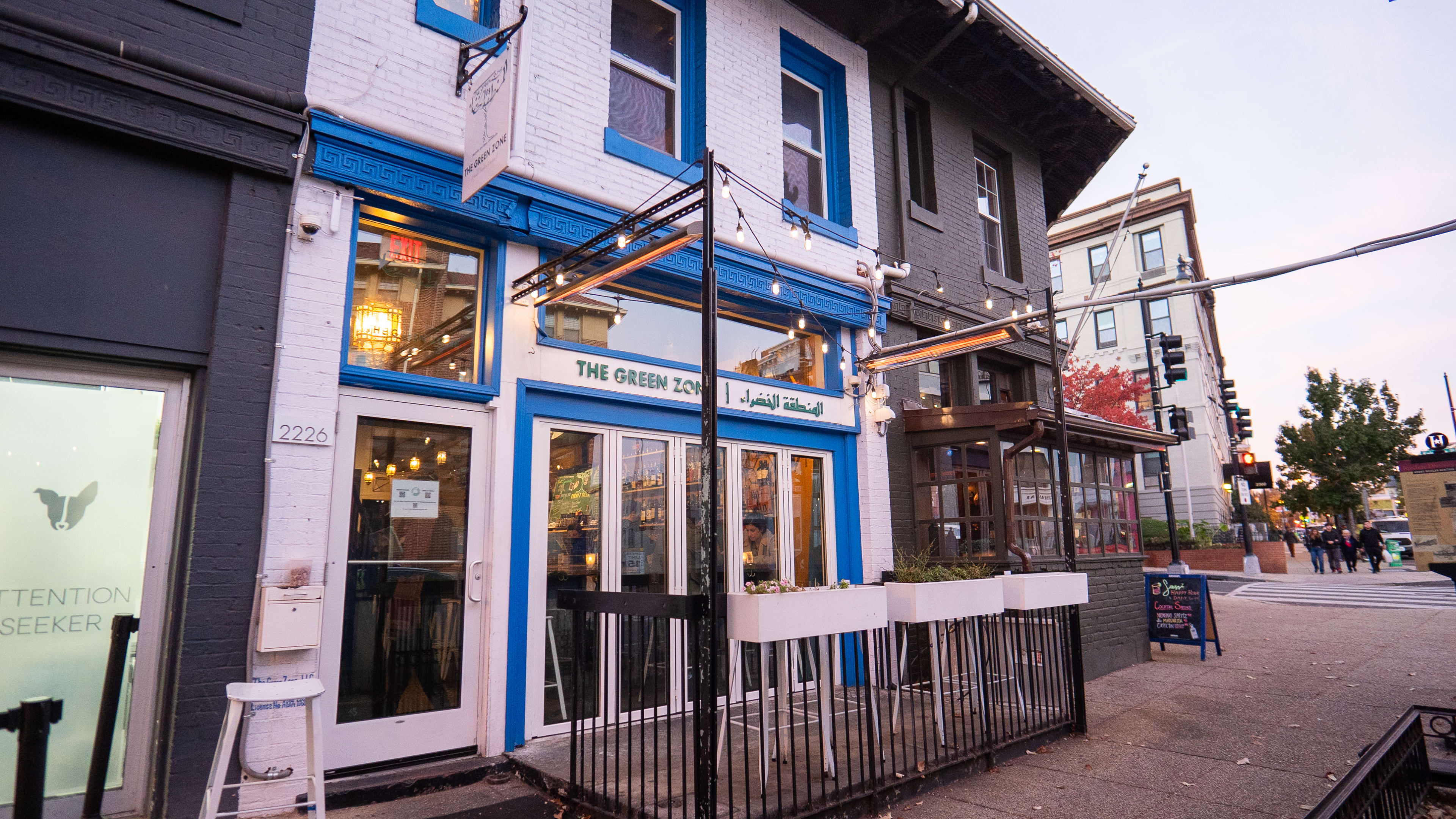 Two-story exterior with small outdoor heated patio filled with stools.