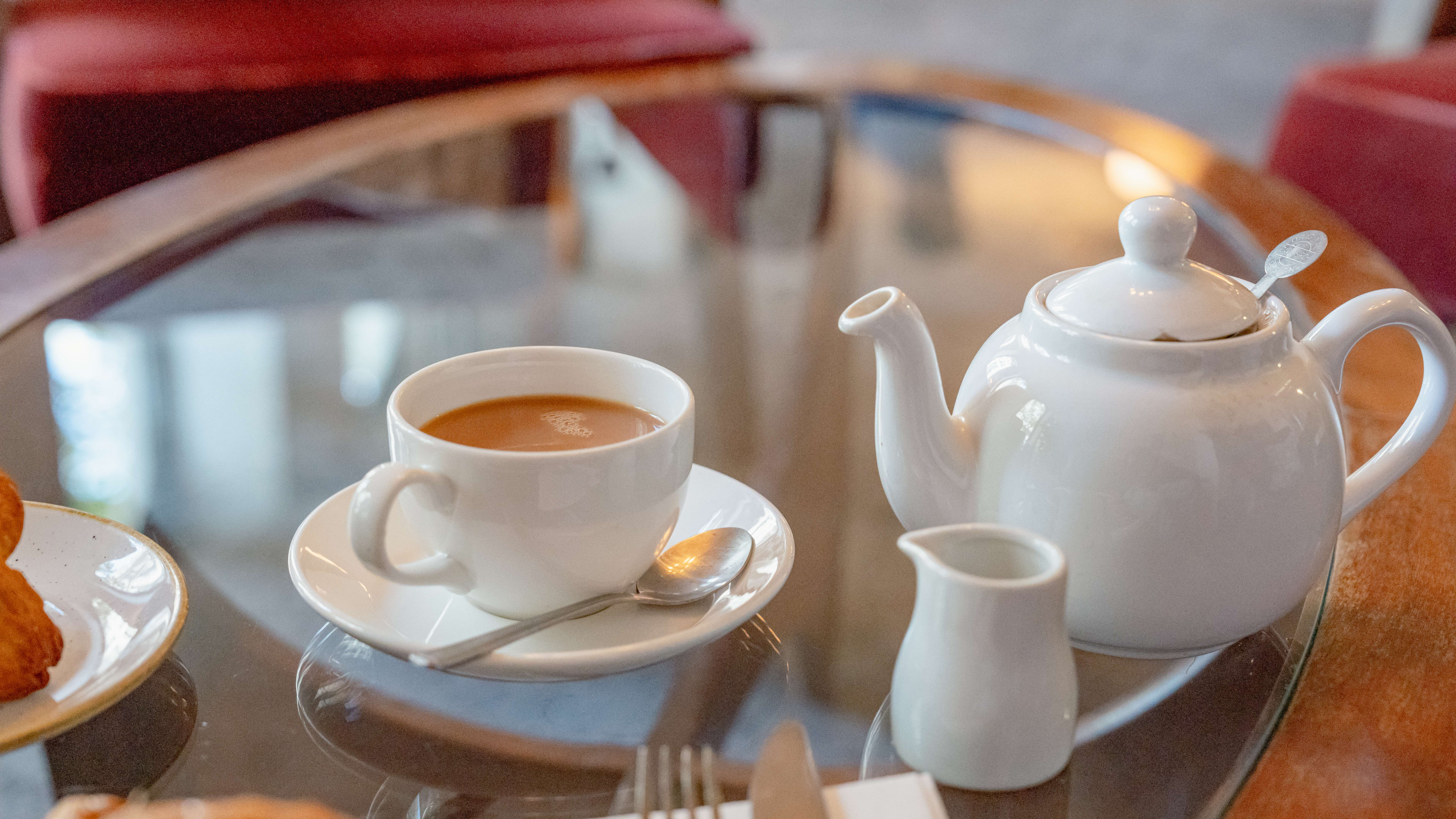 A white pot of tea, a tea cup, and a creamer pot.