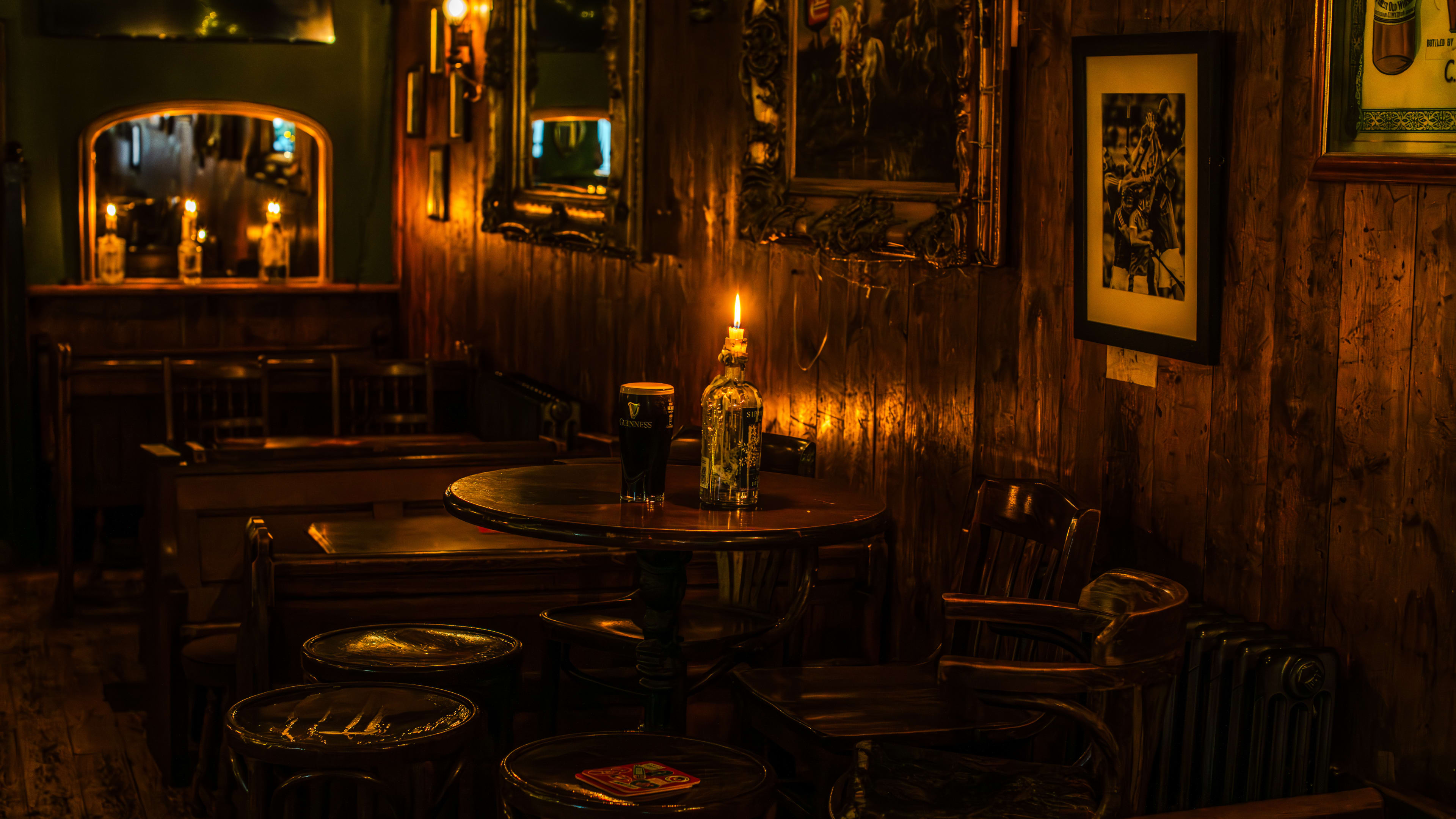 A candle-lit wooden table, wooden walls and framed photos and mirrors on the walls.