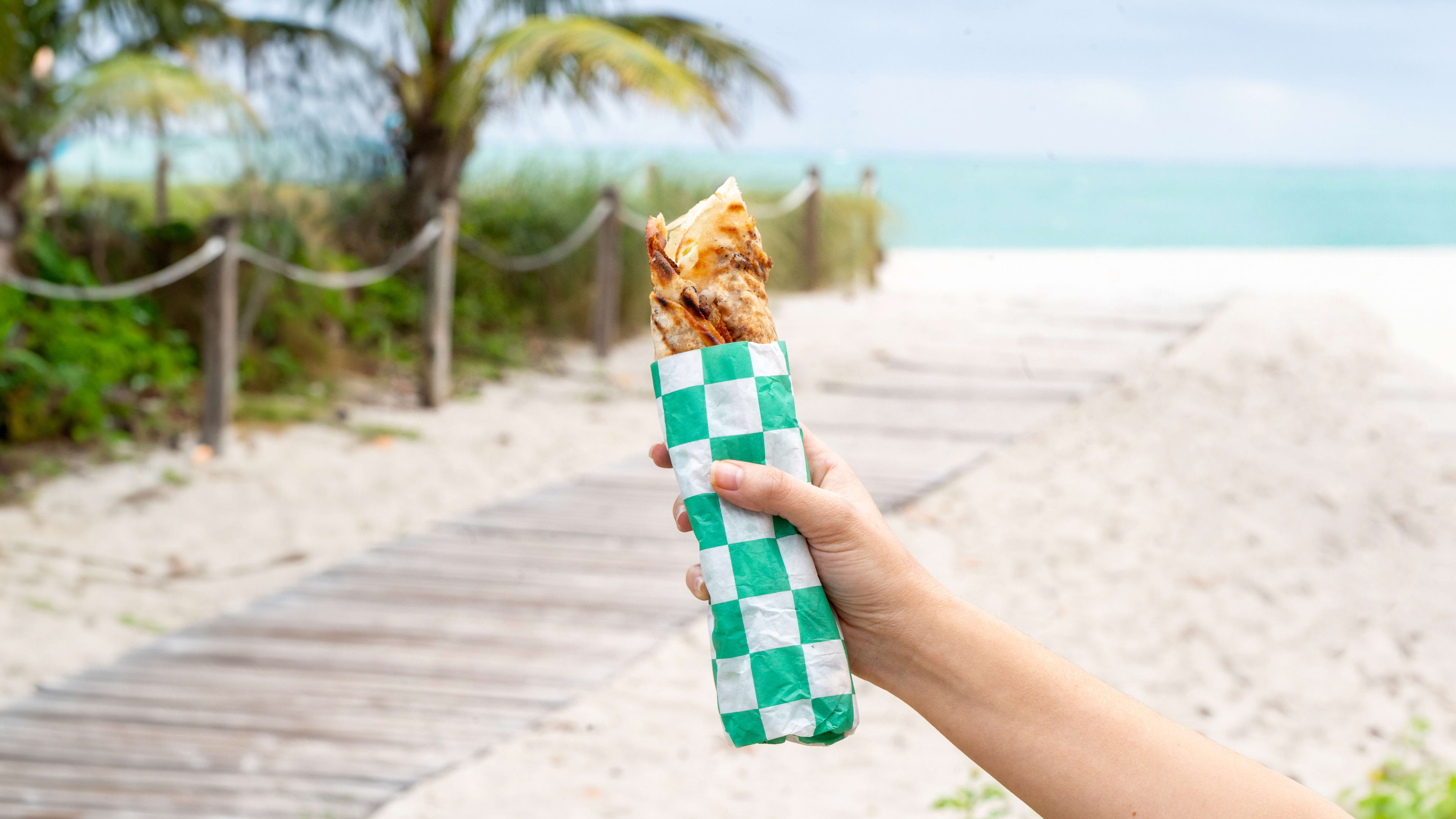 Hand holding wrap up to sandy beach background