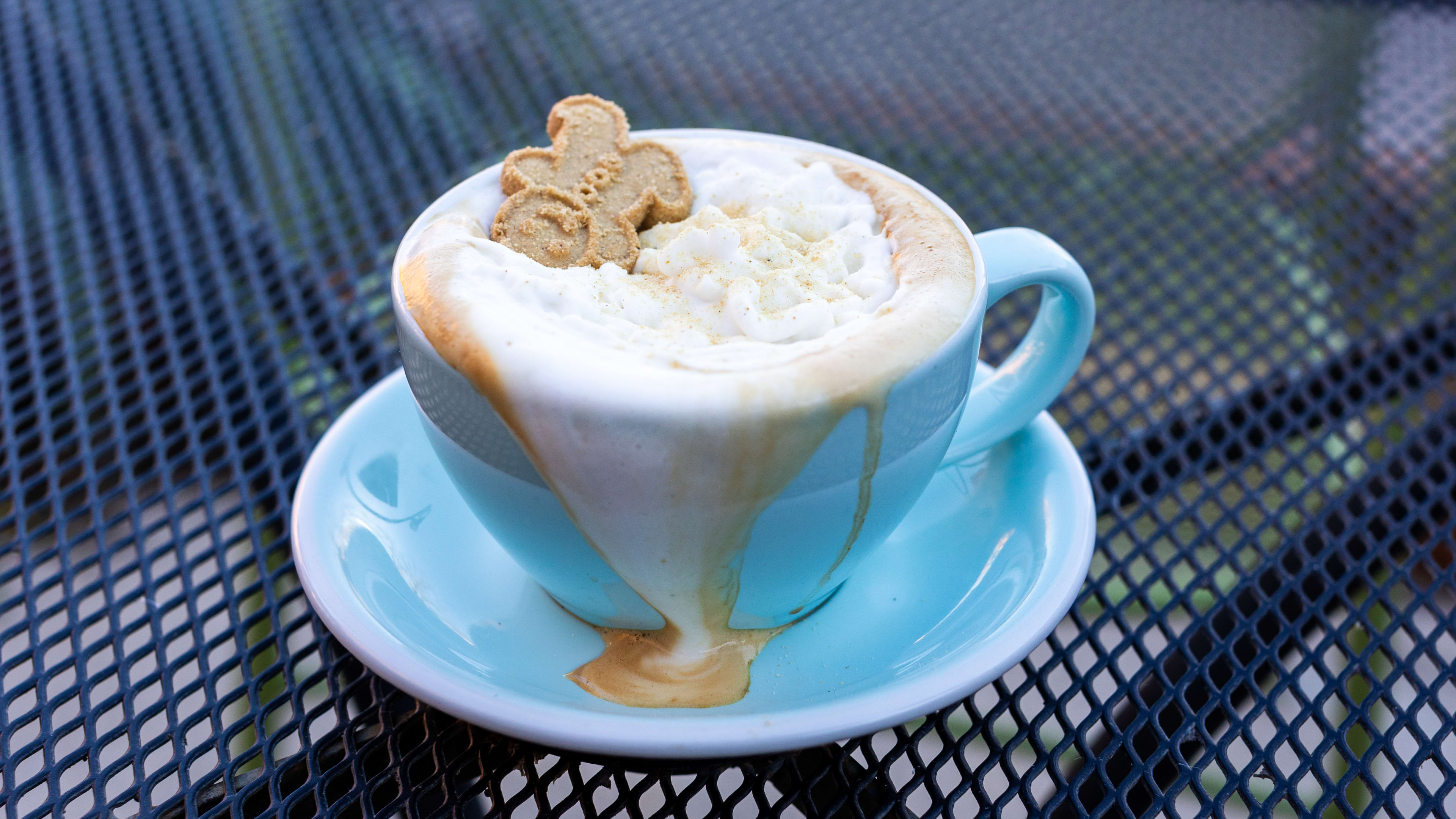 The Not My Gum Drop Buttons coffee drink served in a blue mug with a gingerbread cookie on top.