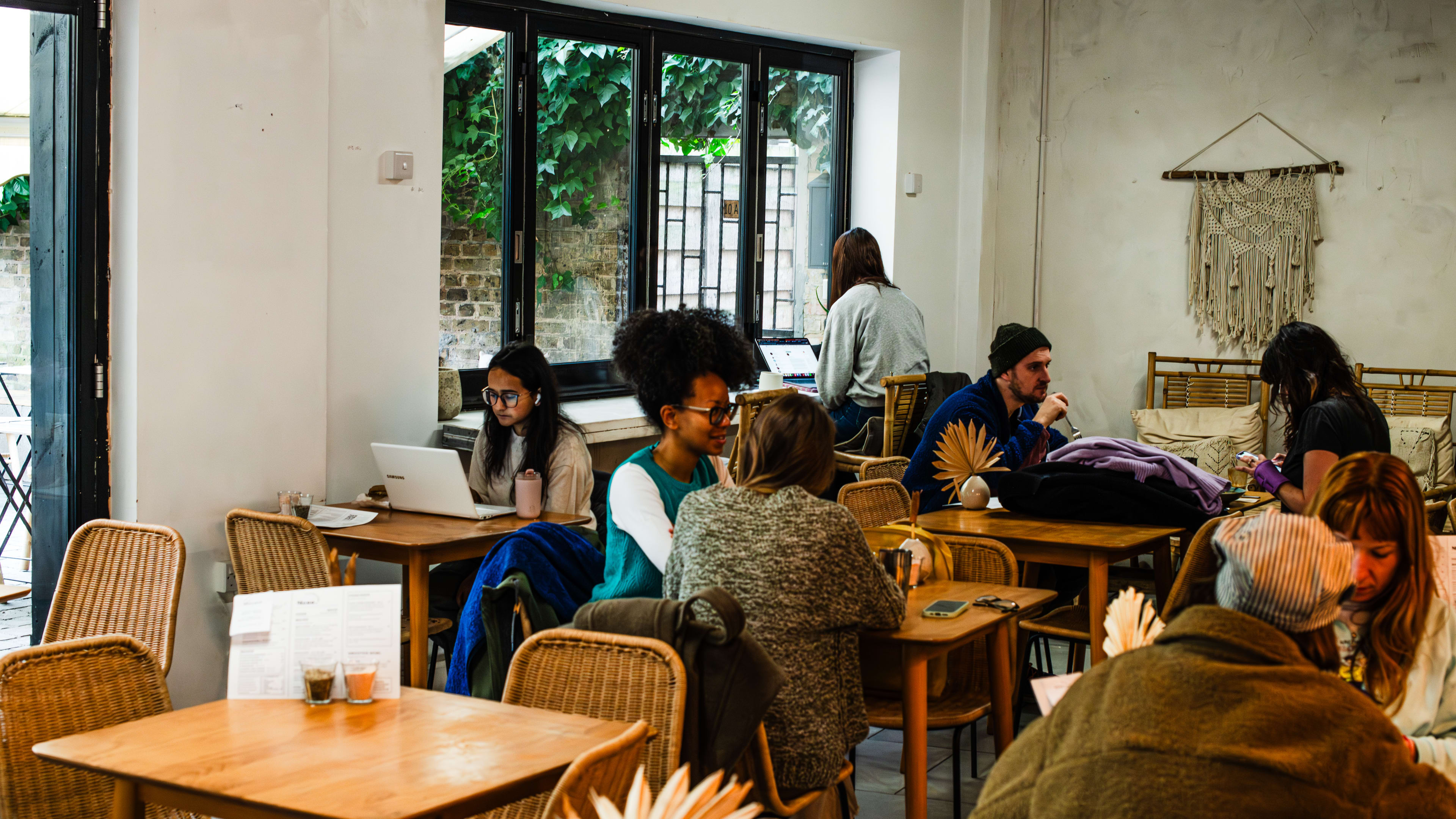 People sitting on ratten chairs in Wave, a vegan cafe in Hackney.