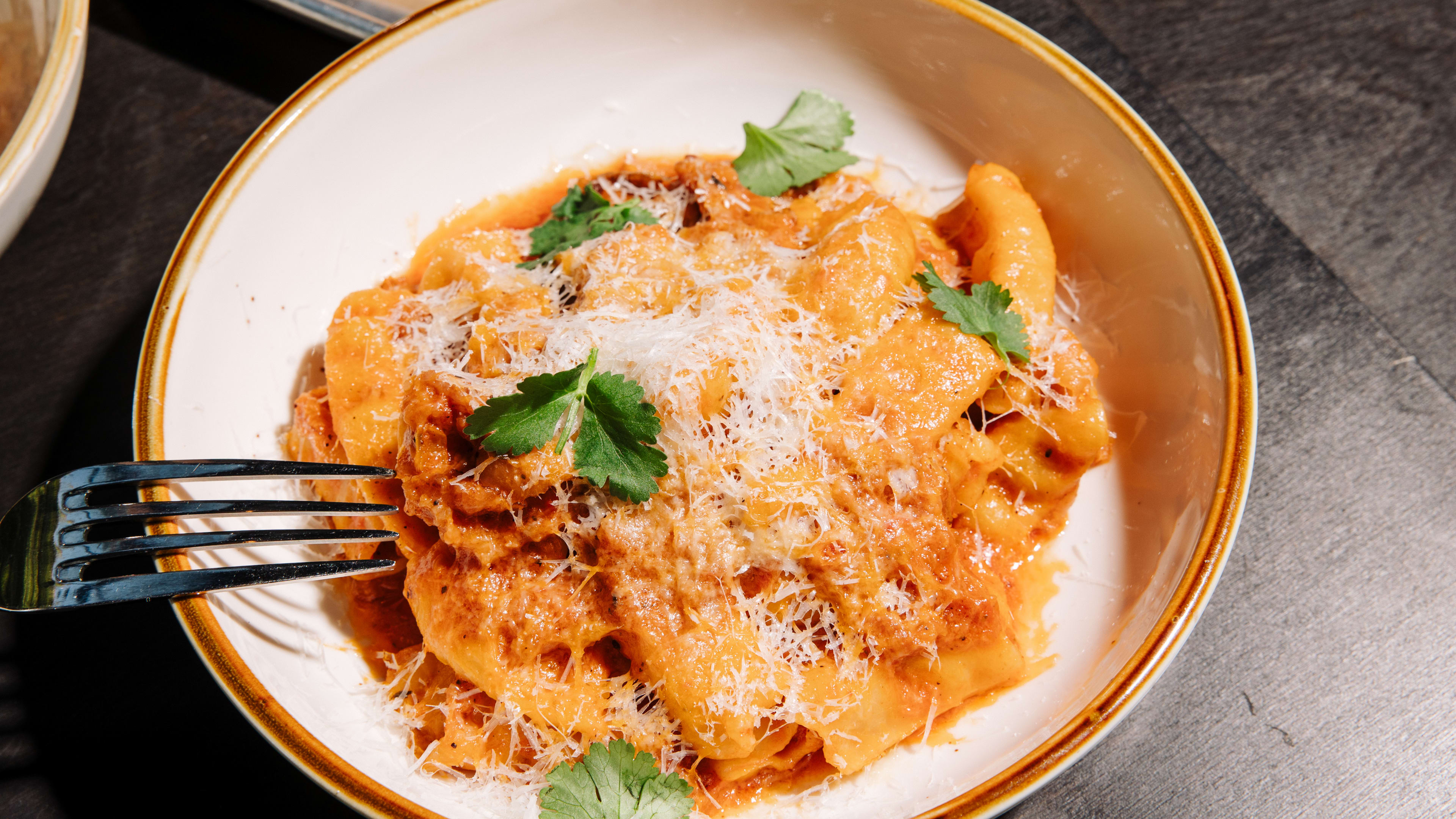 Bowl of pasta with tomato sauce sprinkled with a few microgreens.