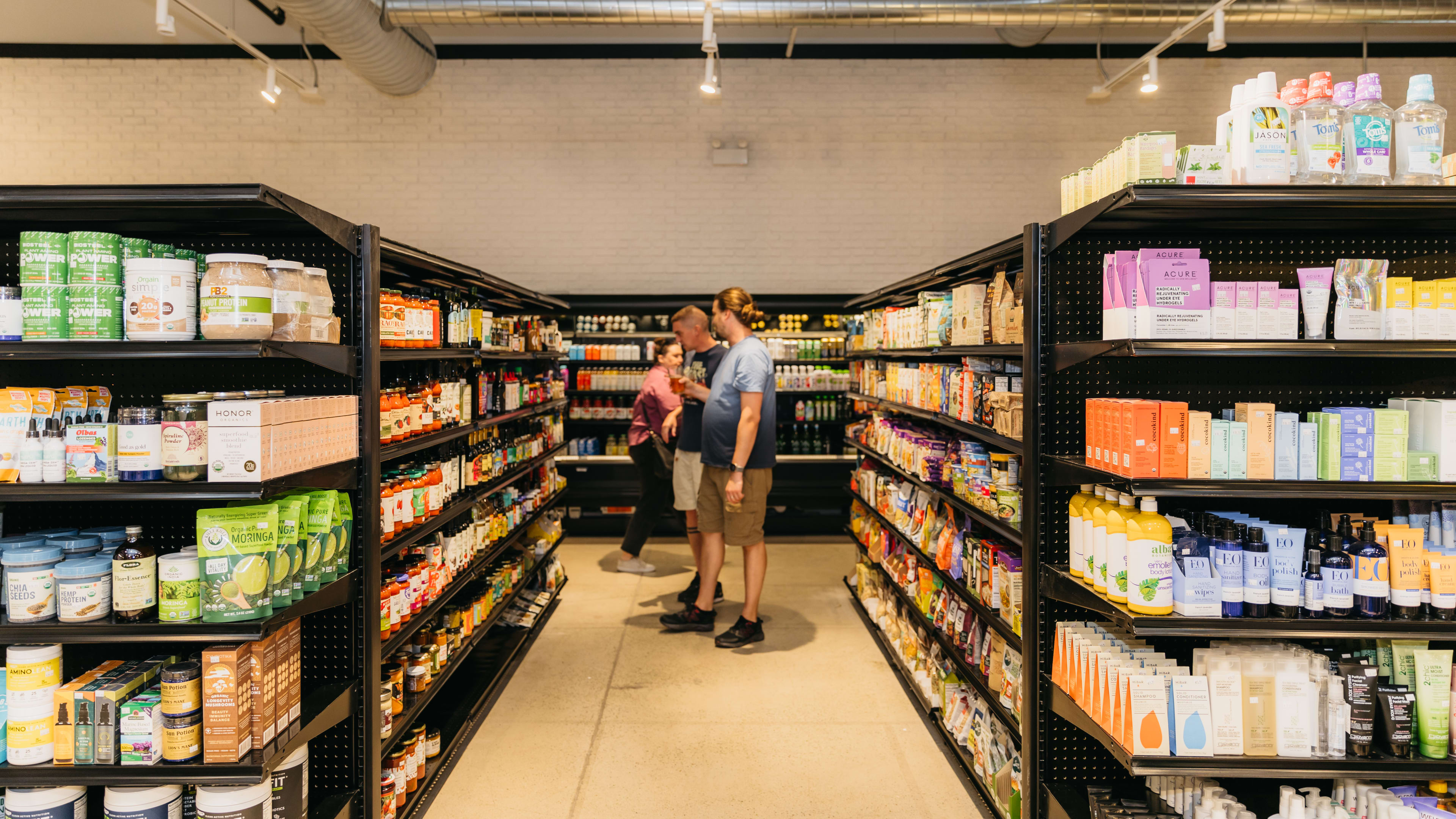 People browsing an aisle including pasta sauce, olive oils, and dry goods at XMarket Food Hall.