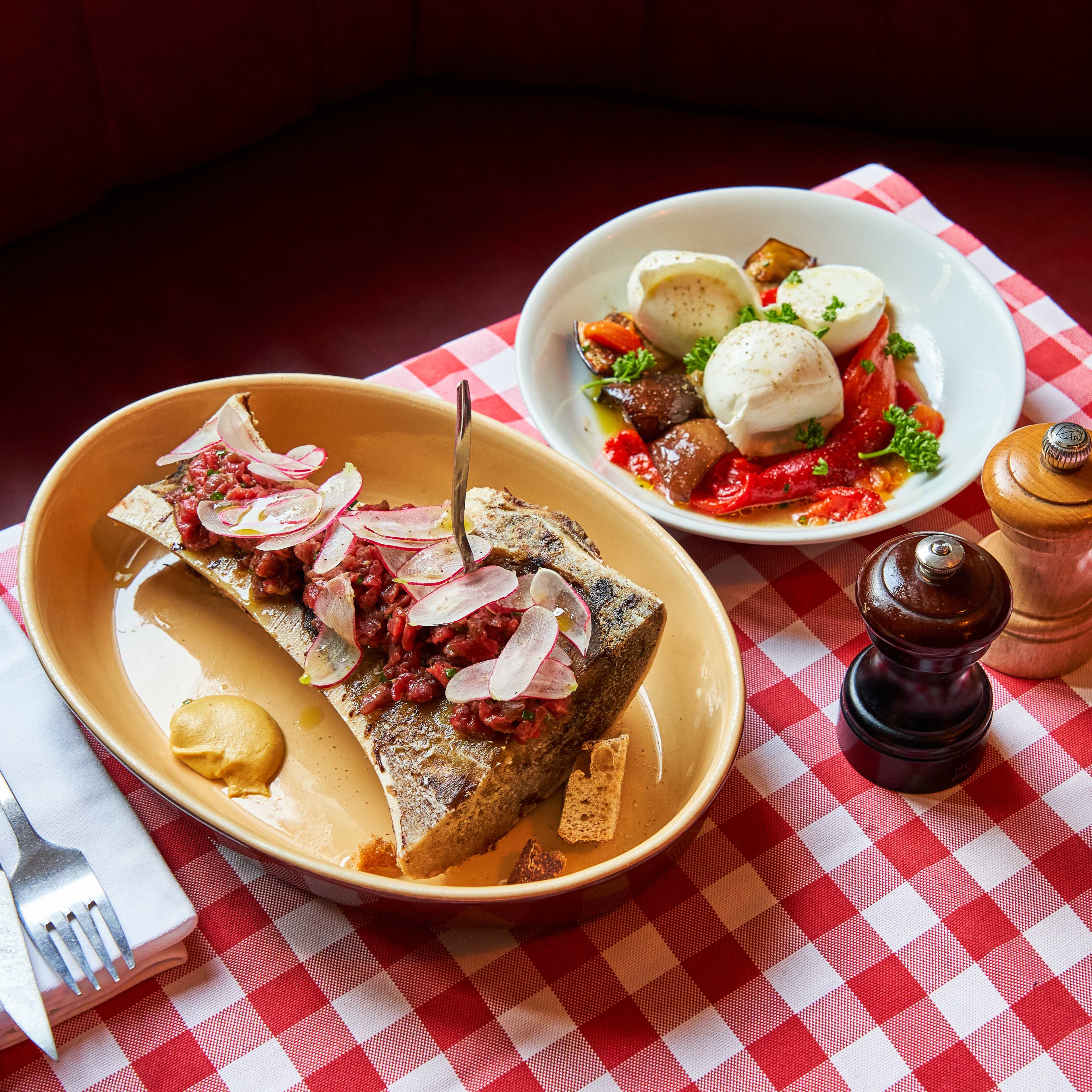 Bone marrow dish with side of mozzarella salad on red checkered tablecloth at Chez Marius