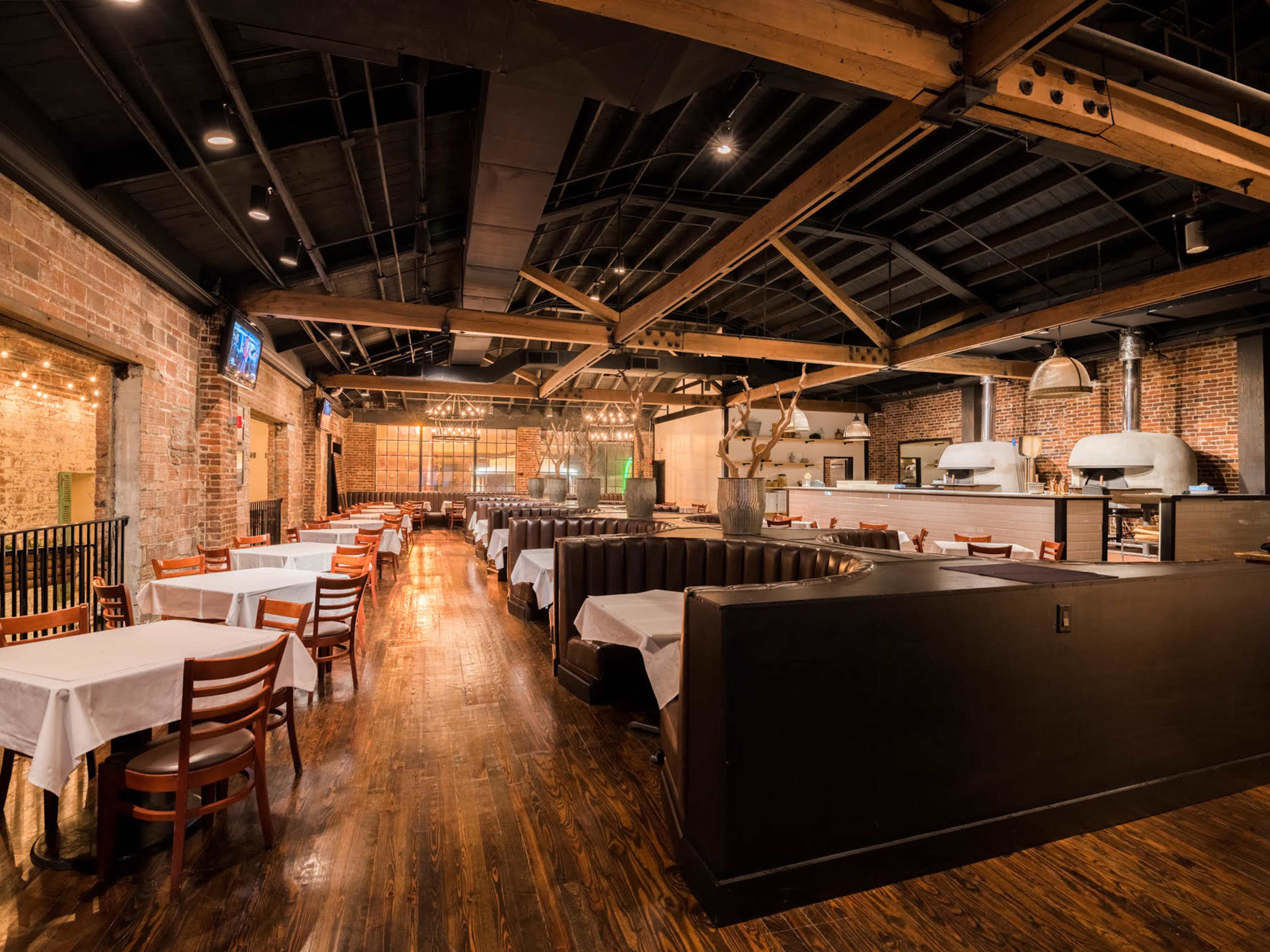 dark moody italian restaurant interior with big leather booths and exposed brick walls