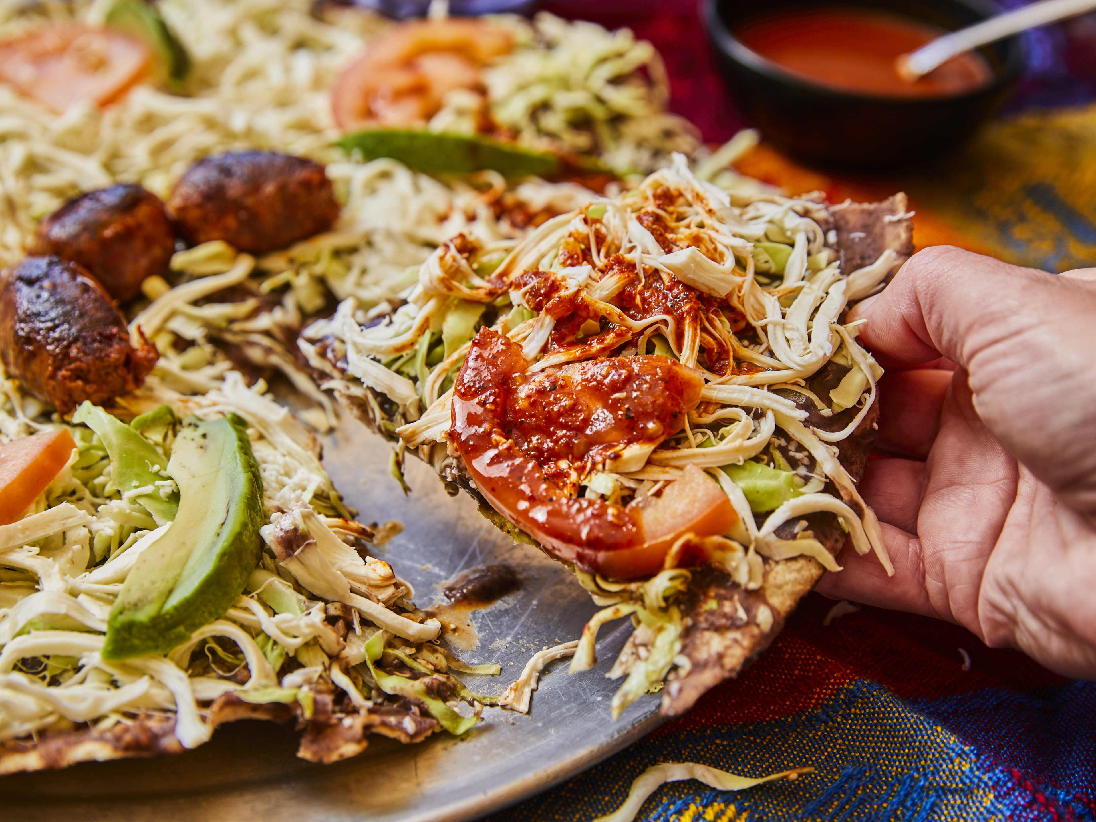 A slice of salsa covered tlayuda from Las 7 Regiones De Oaxaca.