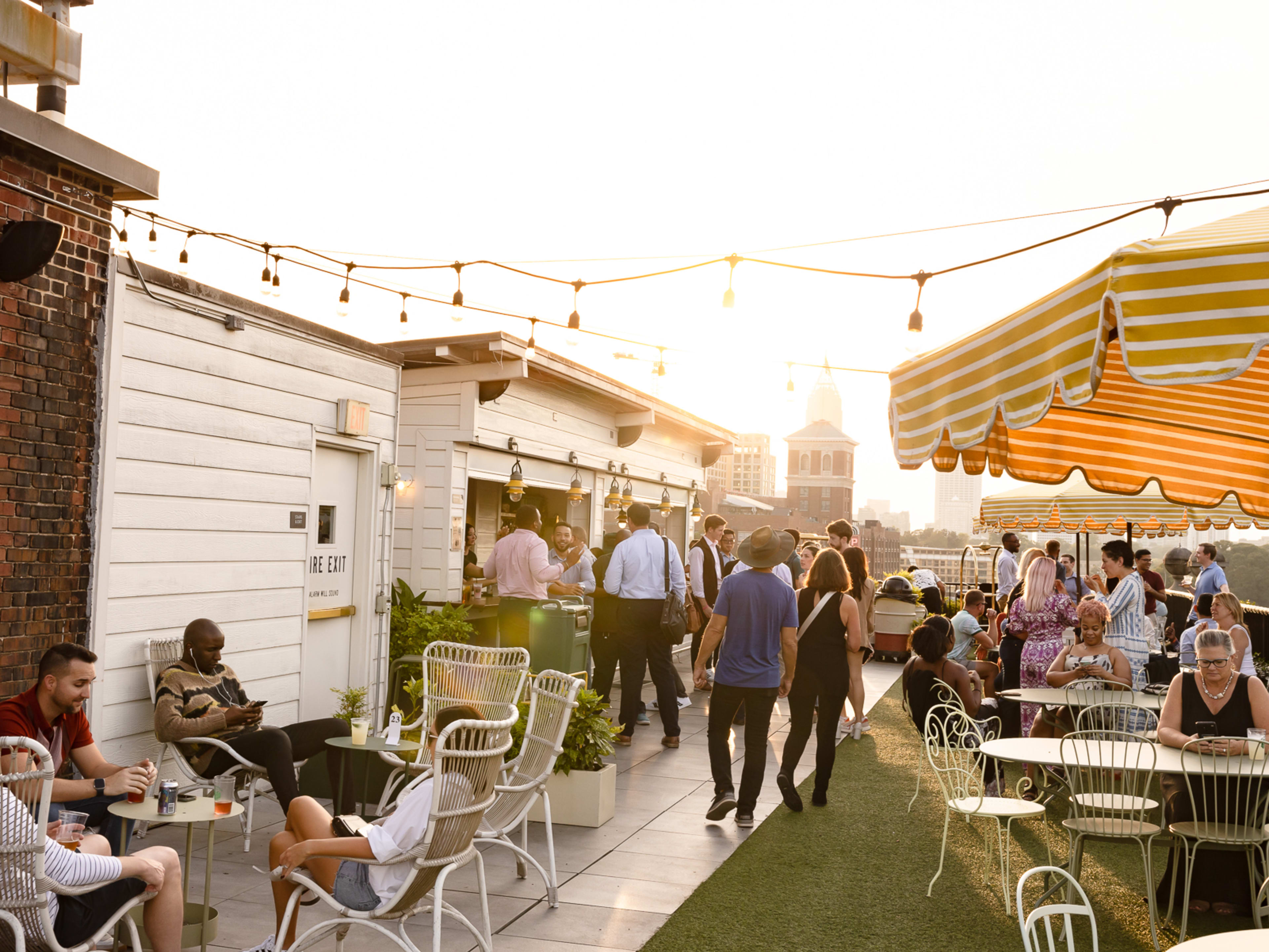 A rooftop filled with people as sun creeps out from behind buildings.