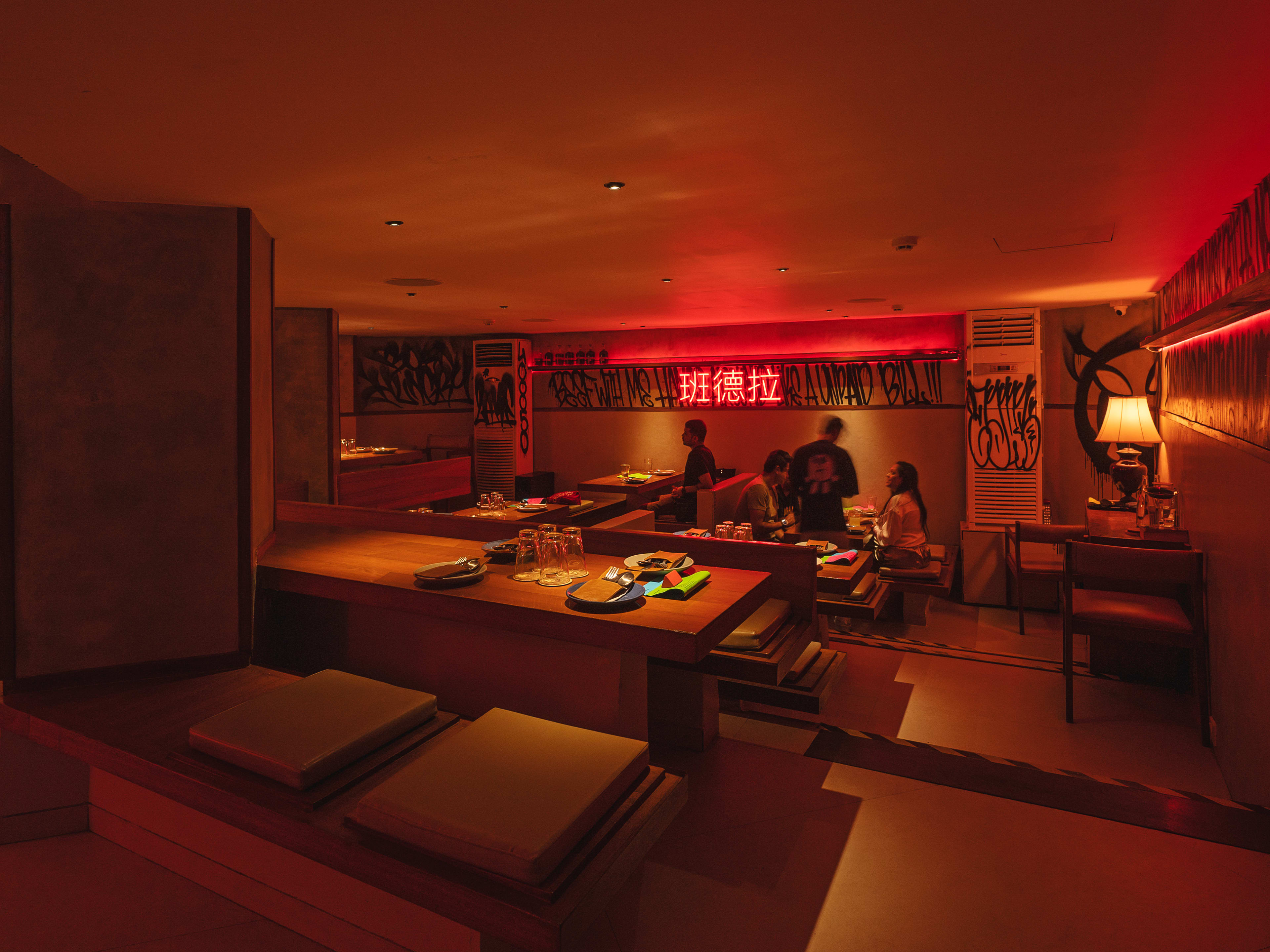 Dim interior dining room with red neon lighting at Bandra Born