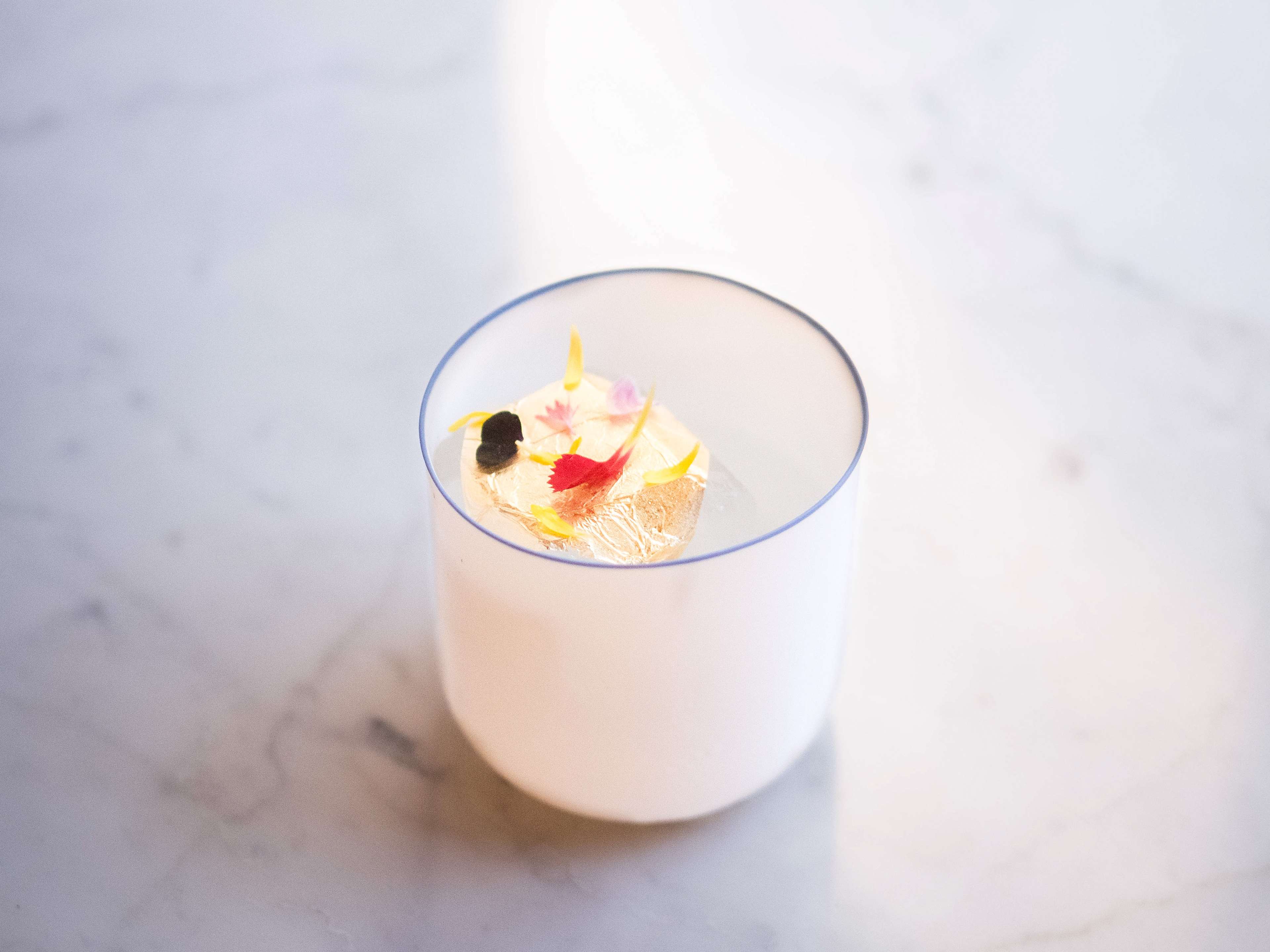 Milky white cocktail topped with edible flowers at Bar Nouveau