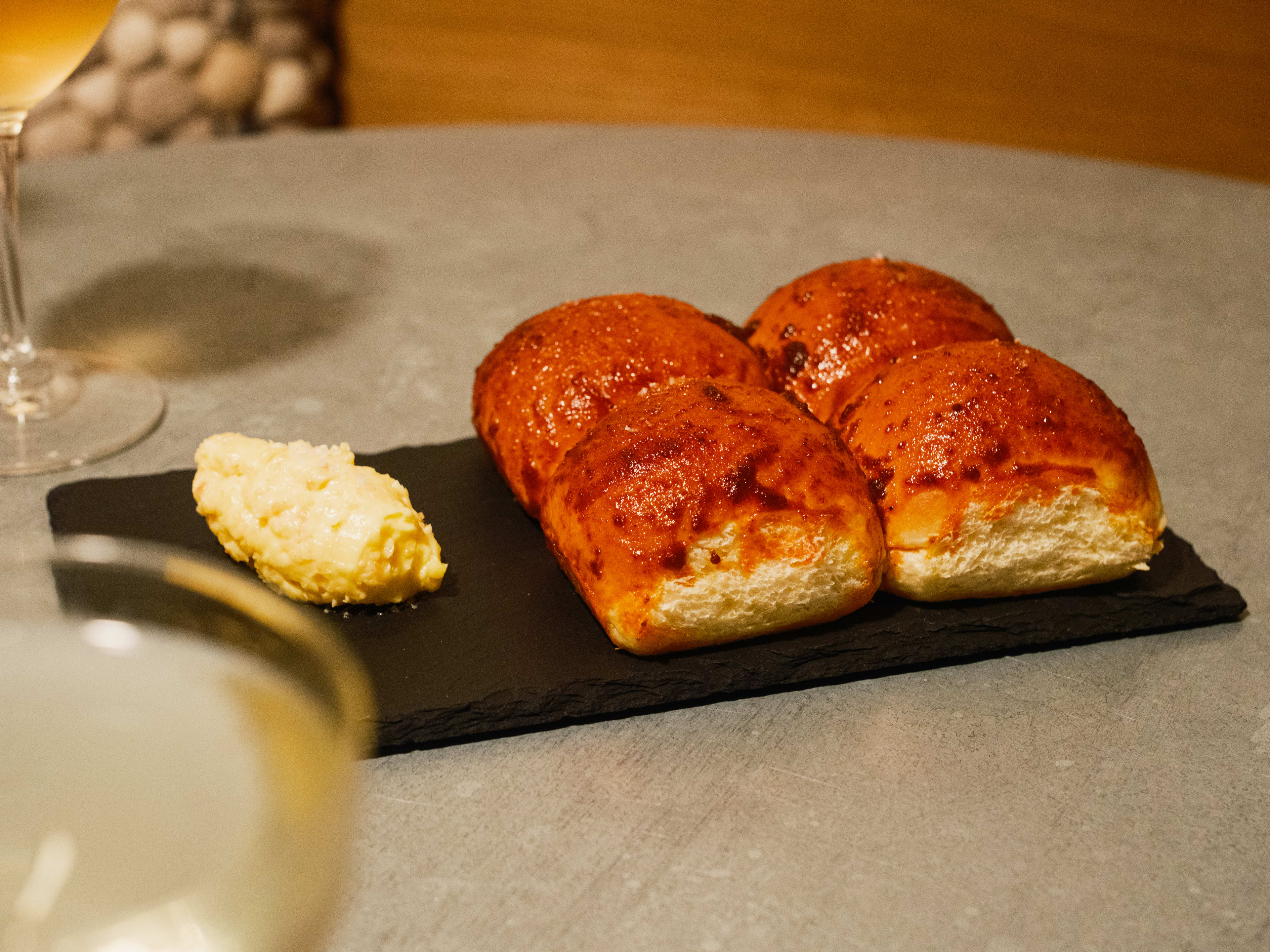 plate of four dinner rolls with small pat of butter on a slate plate