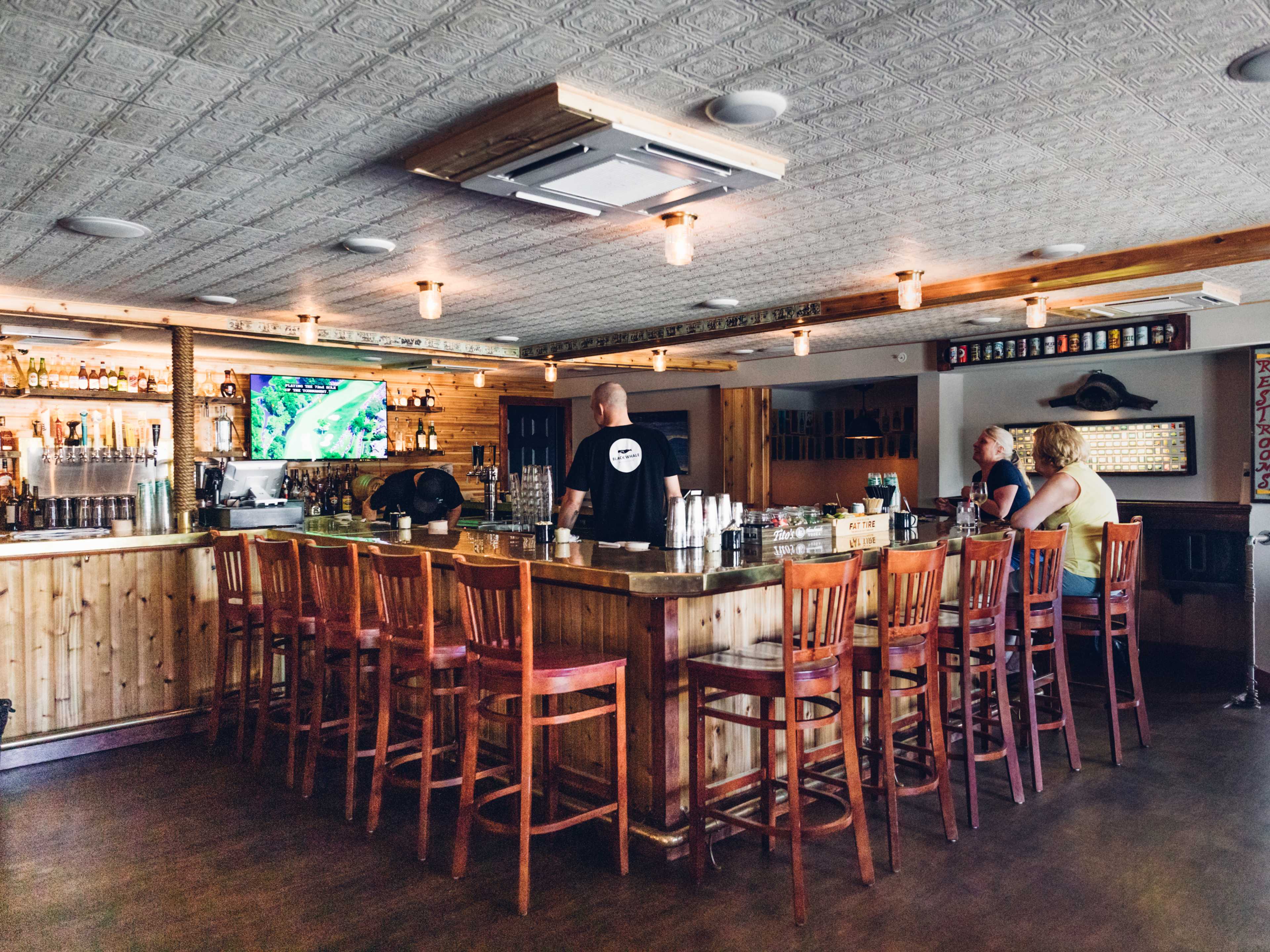 Black whale interiors with a square wooden bar with high top stools