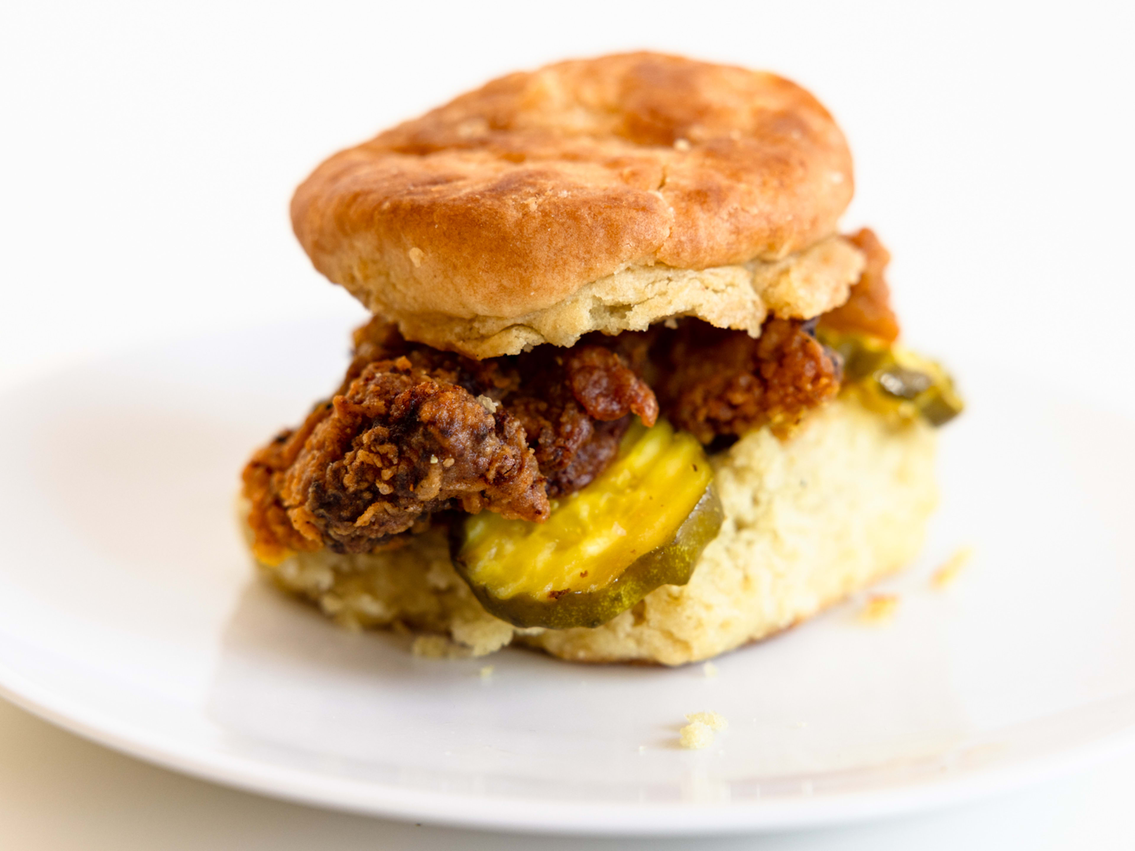 Biscuit with fried chicken and pickles.