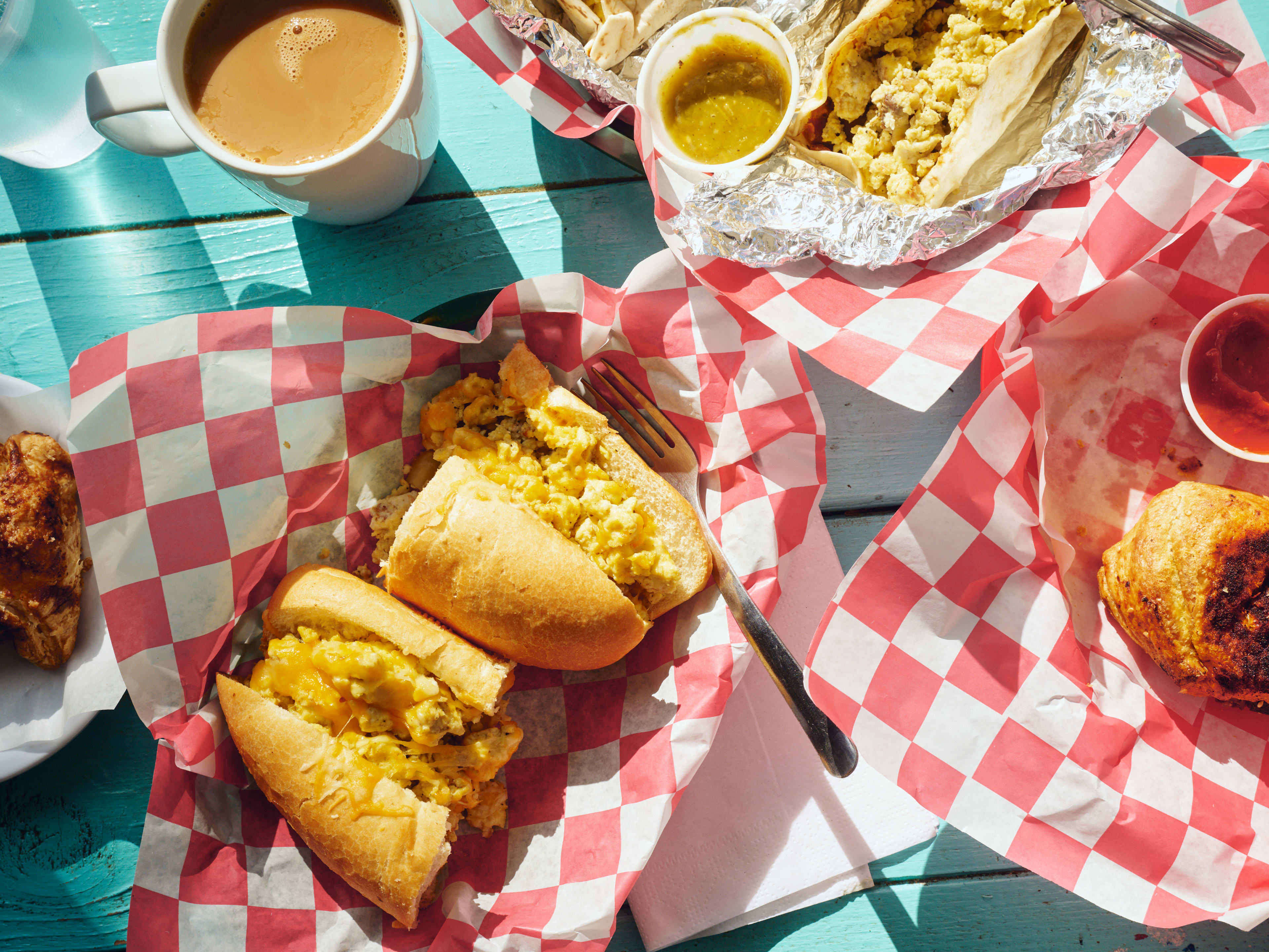 Spread of breakfast sandwiches and tacos on blue painted table at Pagoda Cafe