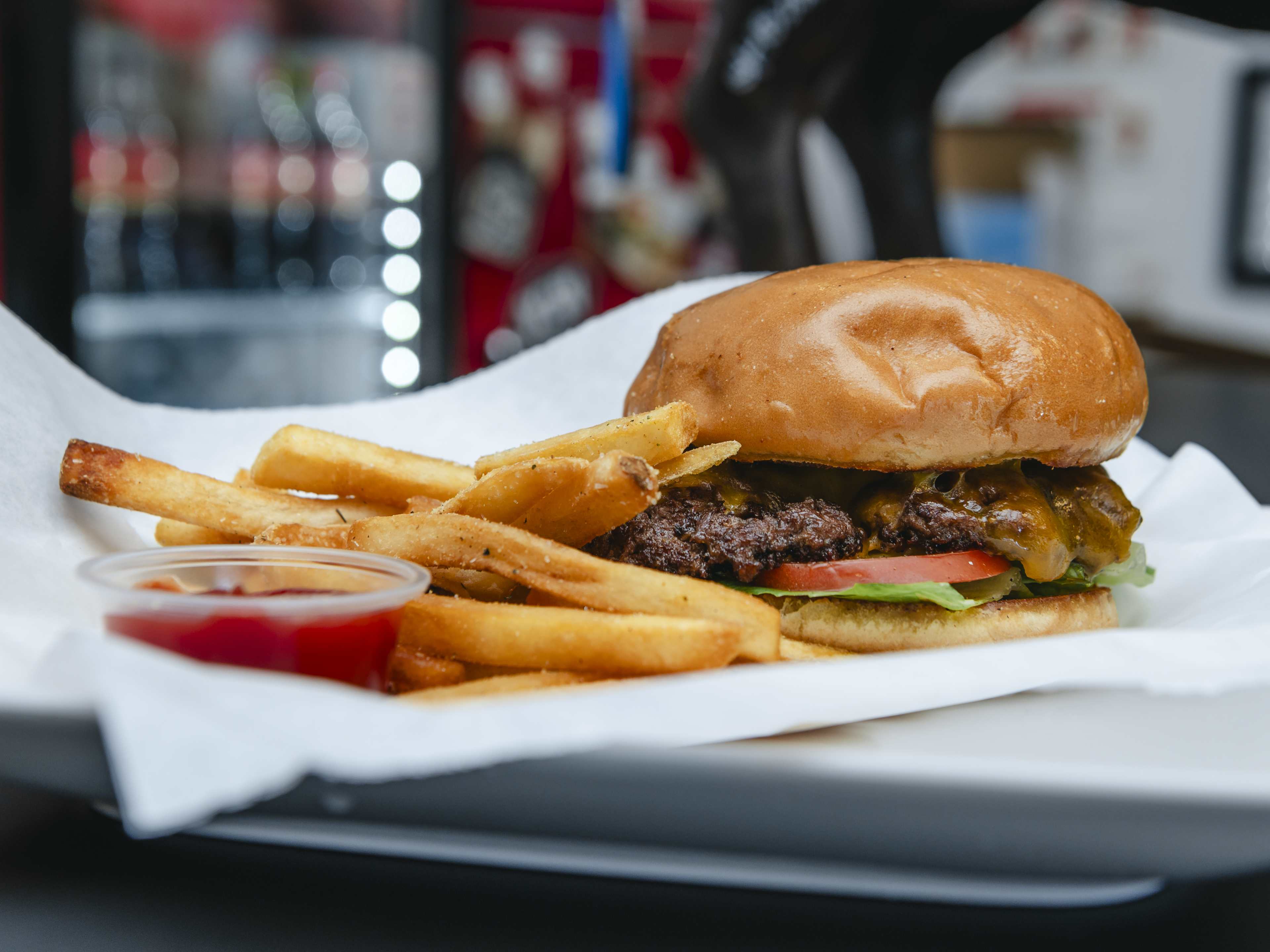 Hamburger with lettuce and tomato on a white plate with fries and ketchup.