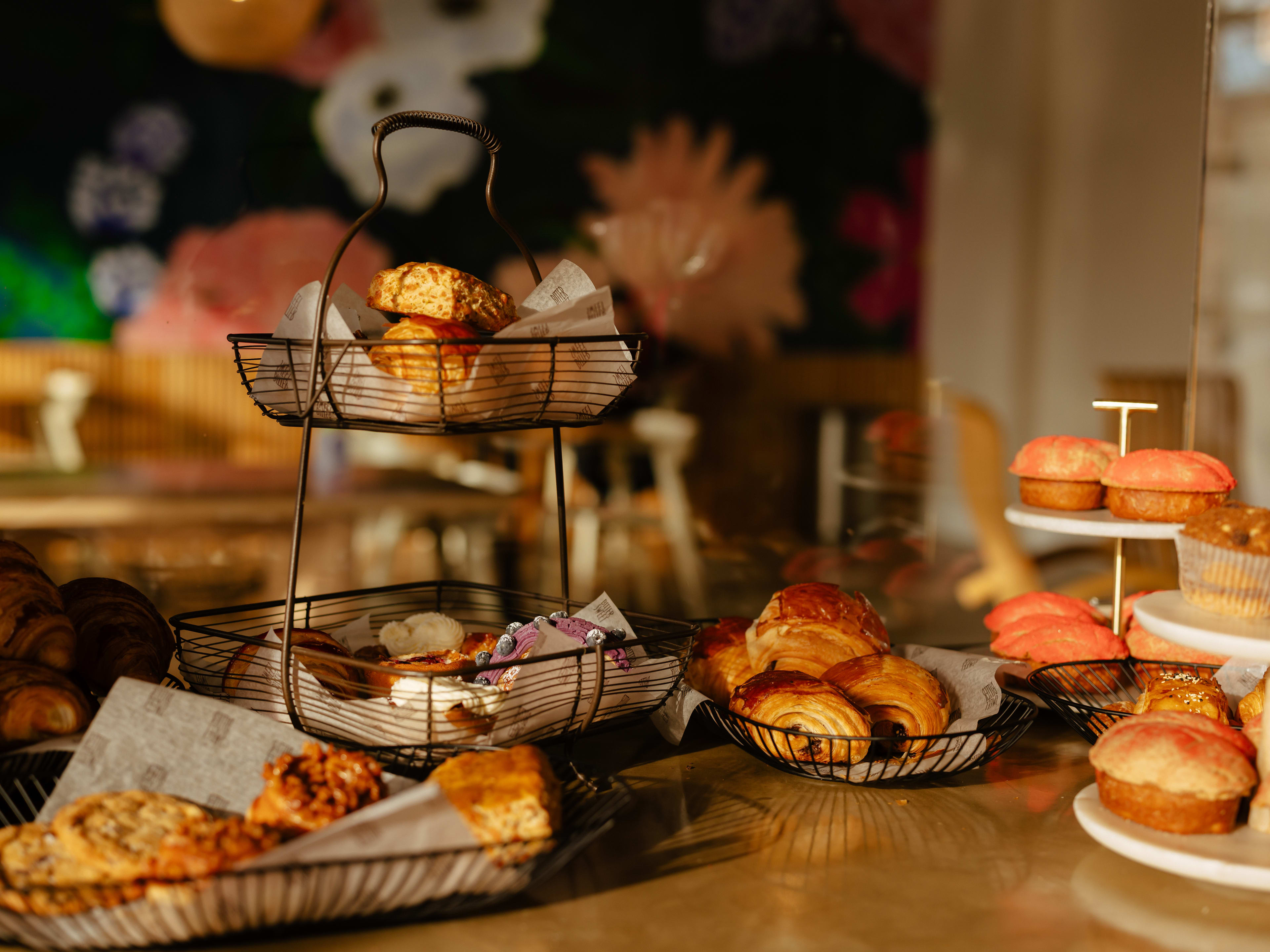 Bittersweet Pastry Shop & Cafe spread of multiple pastries on the counter with a blurred view in to the cafe in the background