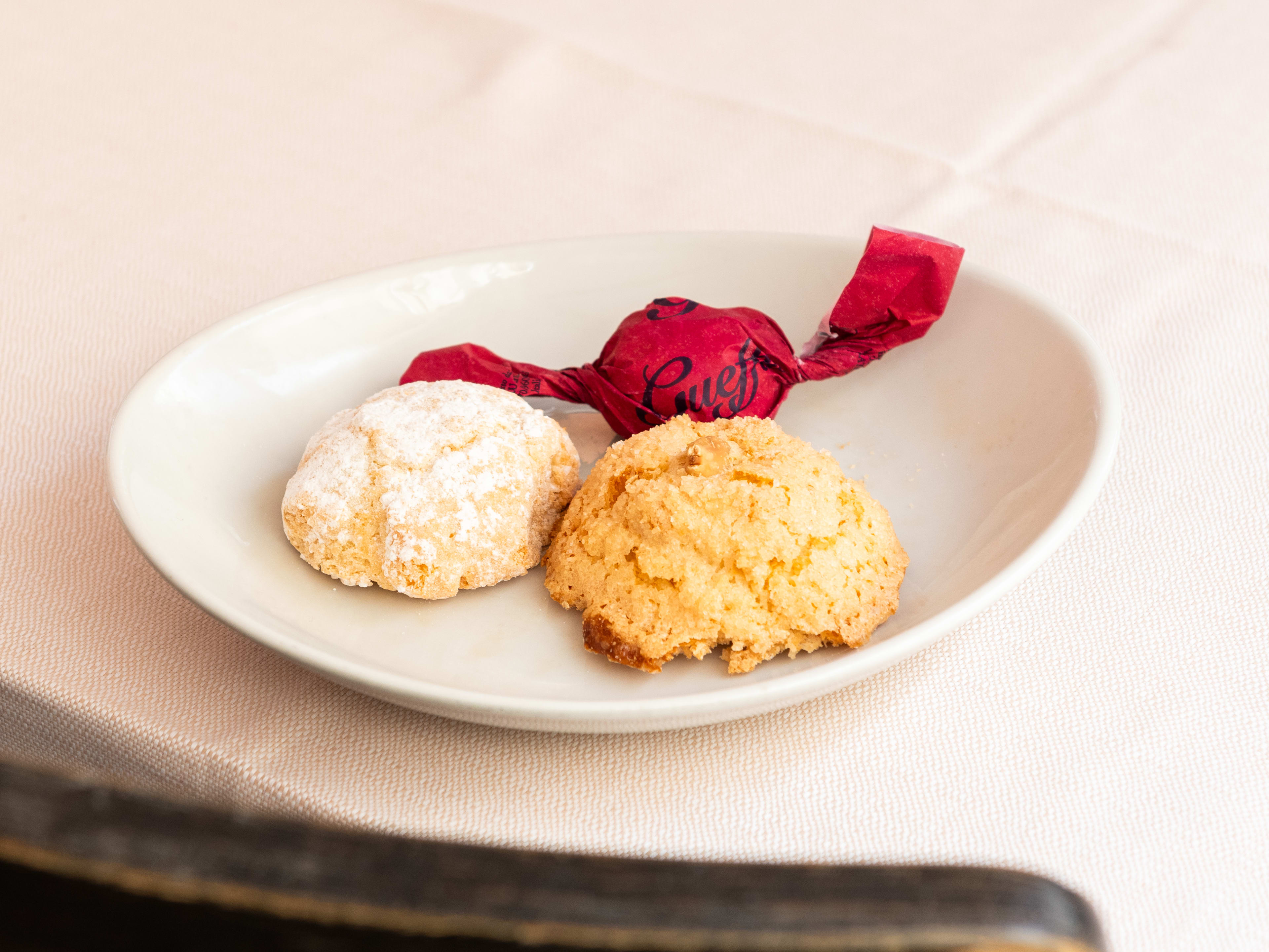 Plate of almond biscuits and wrapped confection at Osteria Der Belli